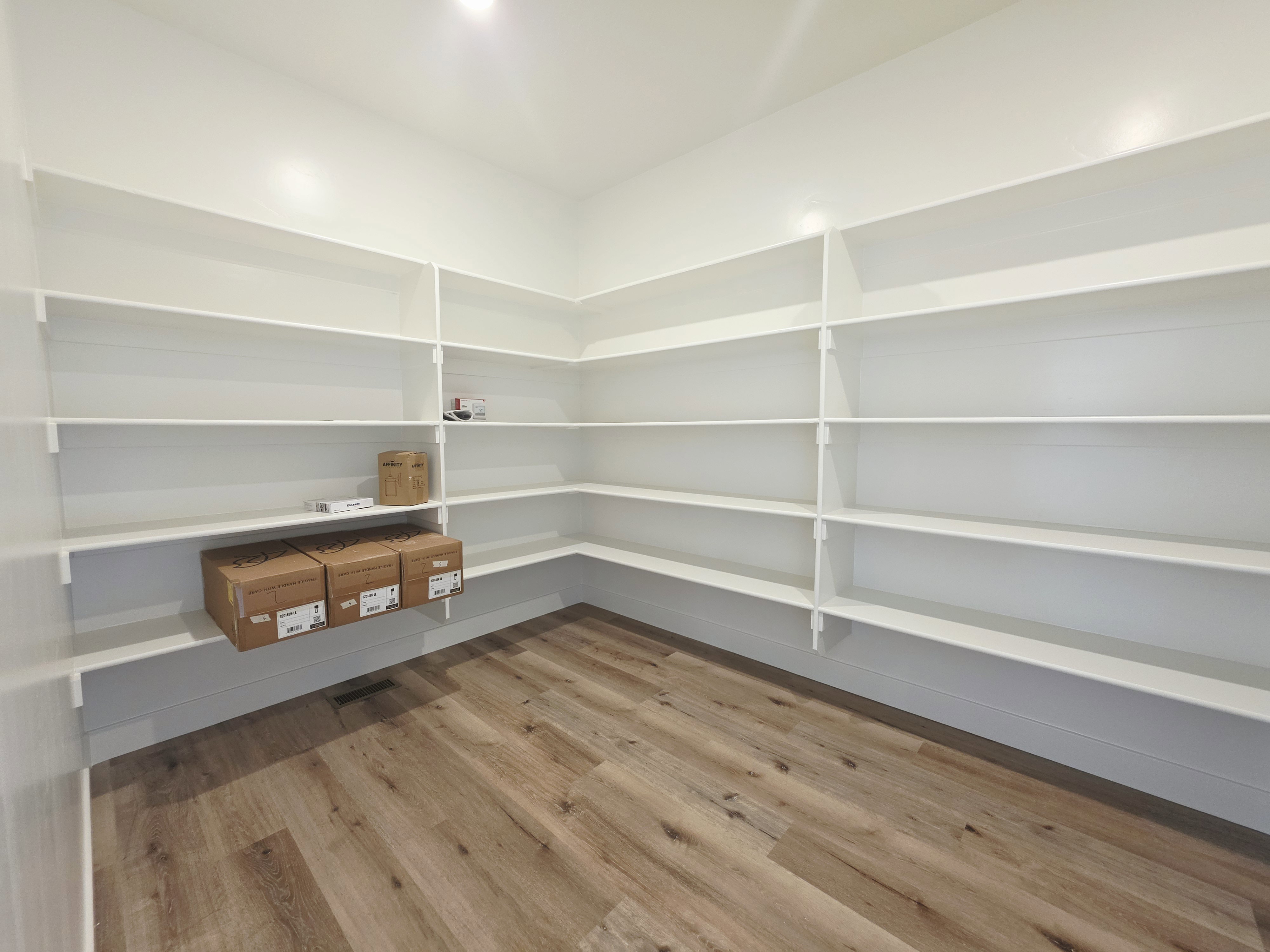 Spacious pantry featuring extensive wrap-around shelving and wood-finish flooring