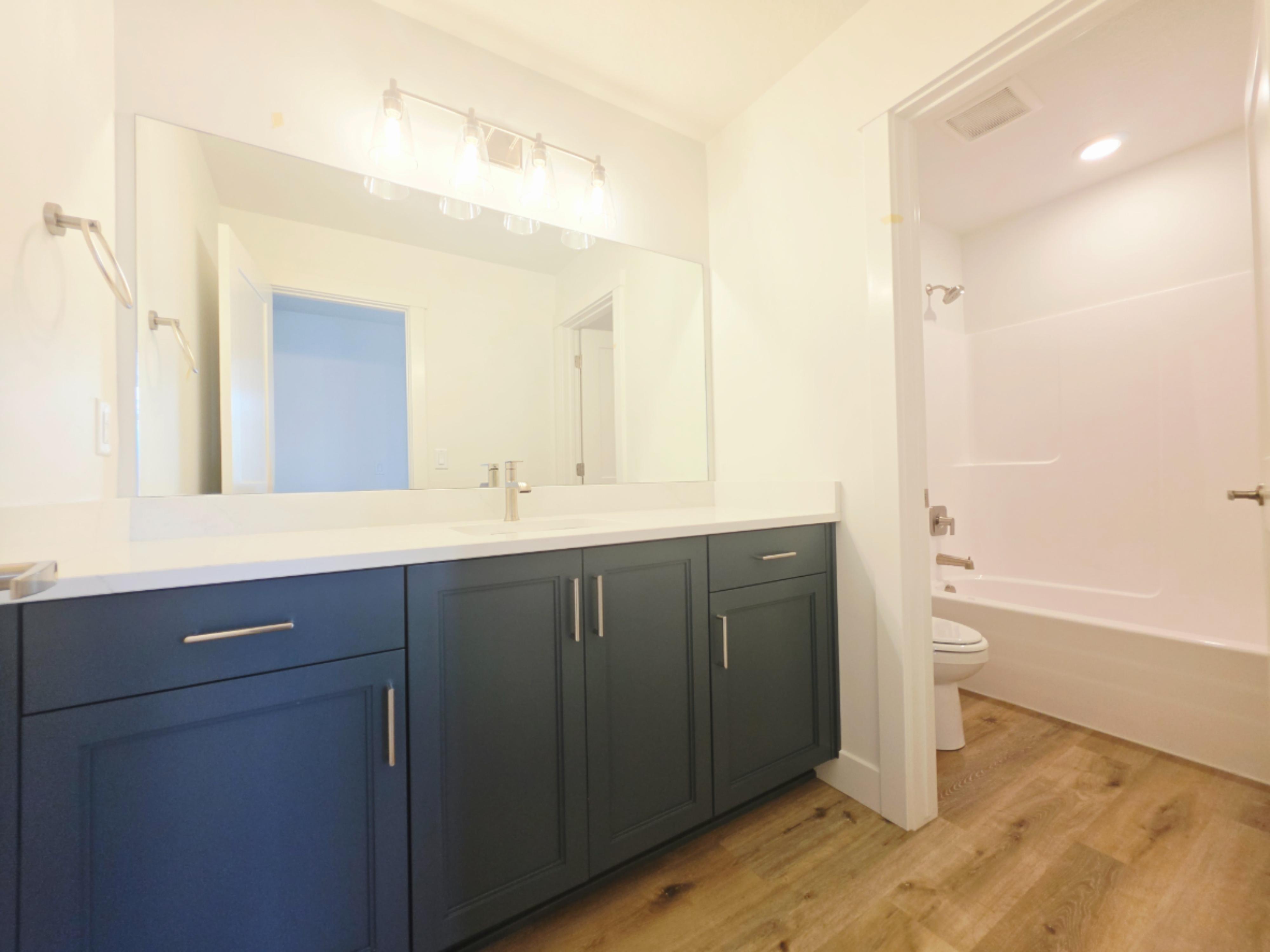 Bathroom featuring a dual-sink vanity with matte blue cabinetry and a white countertop