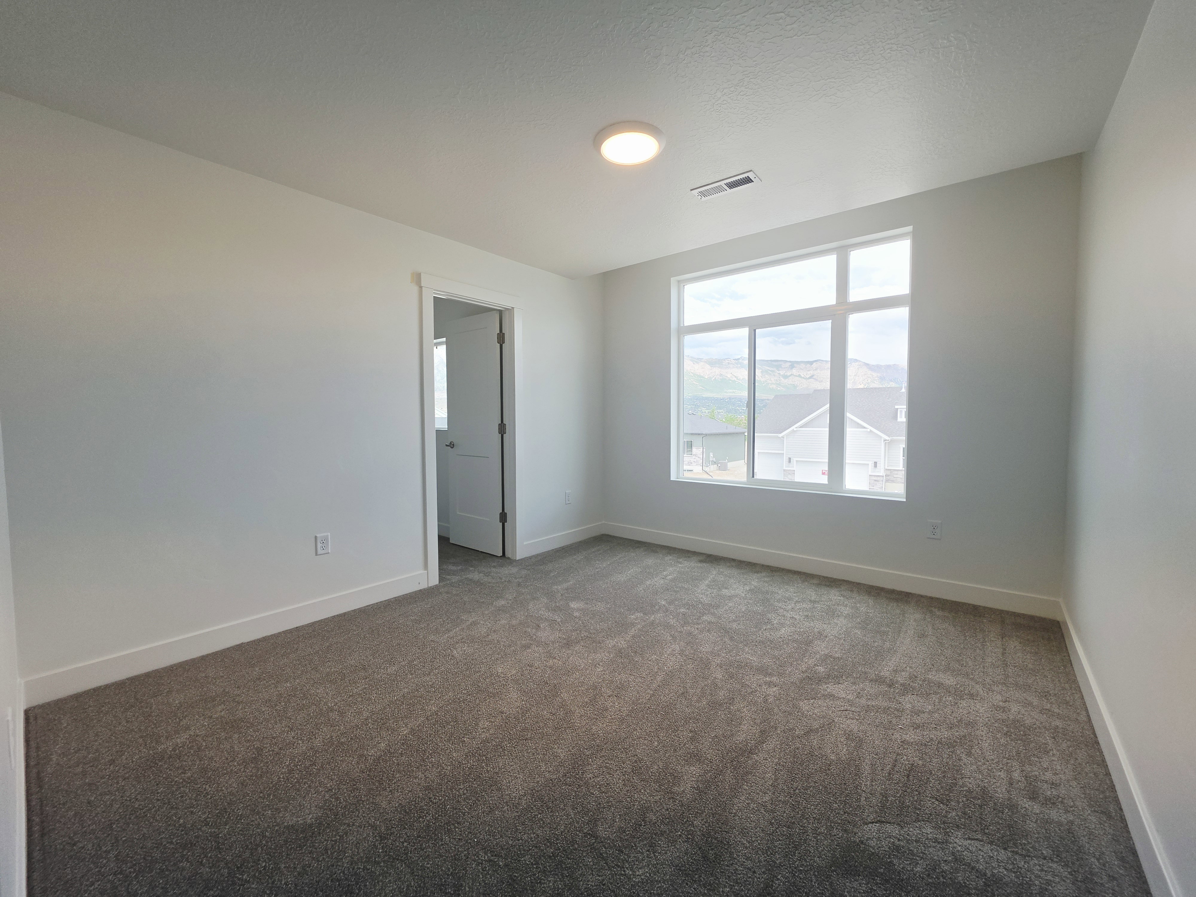 Neutral interior space with a large window, providing natural light and mountain scenery