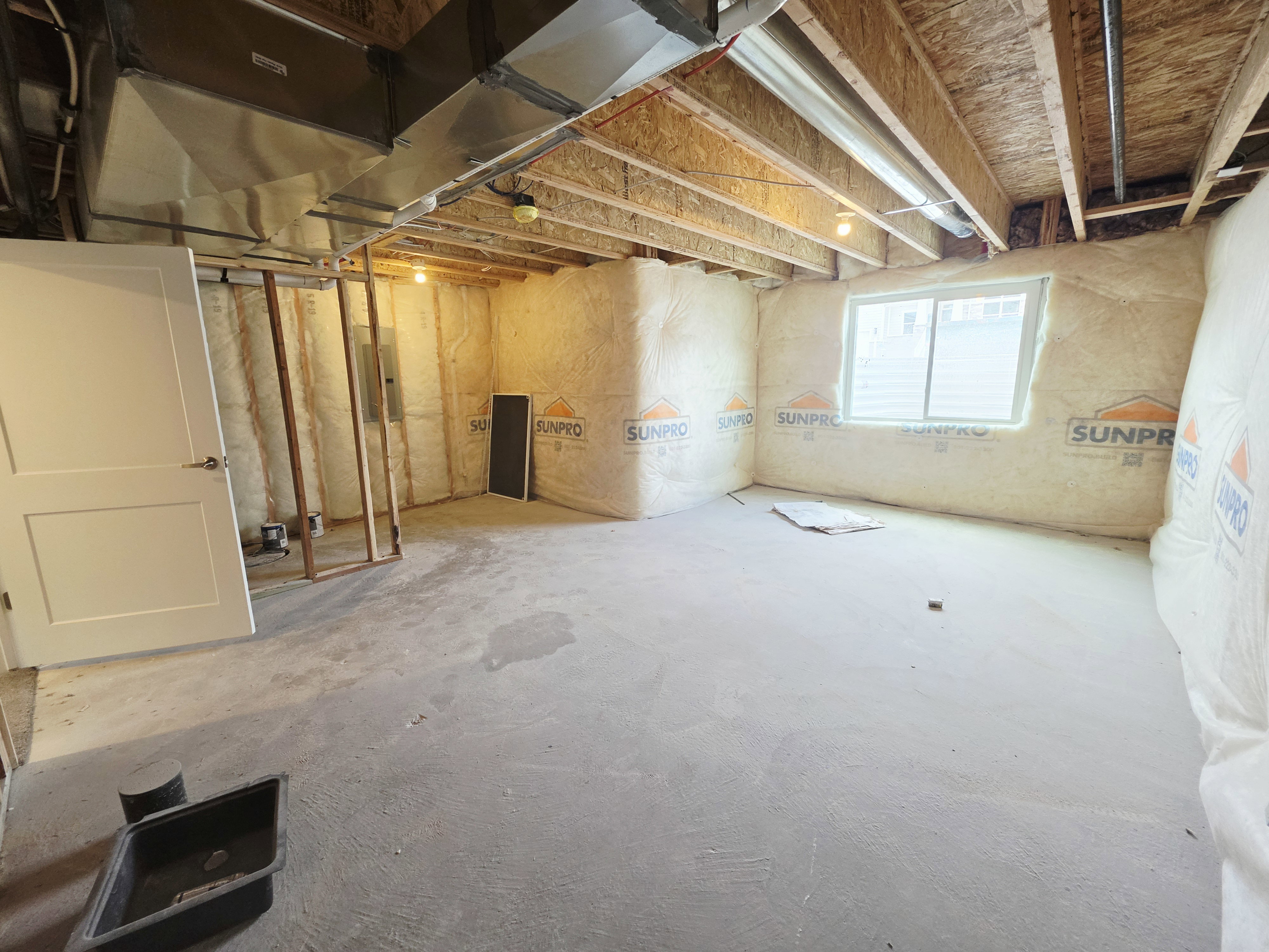 Unfinished basement space featuring exposed ceiling joists, concrete flooring, and insulated walls