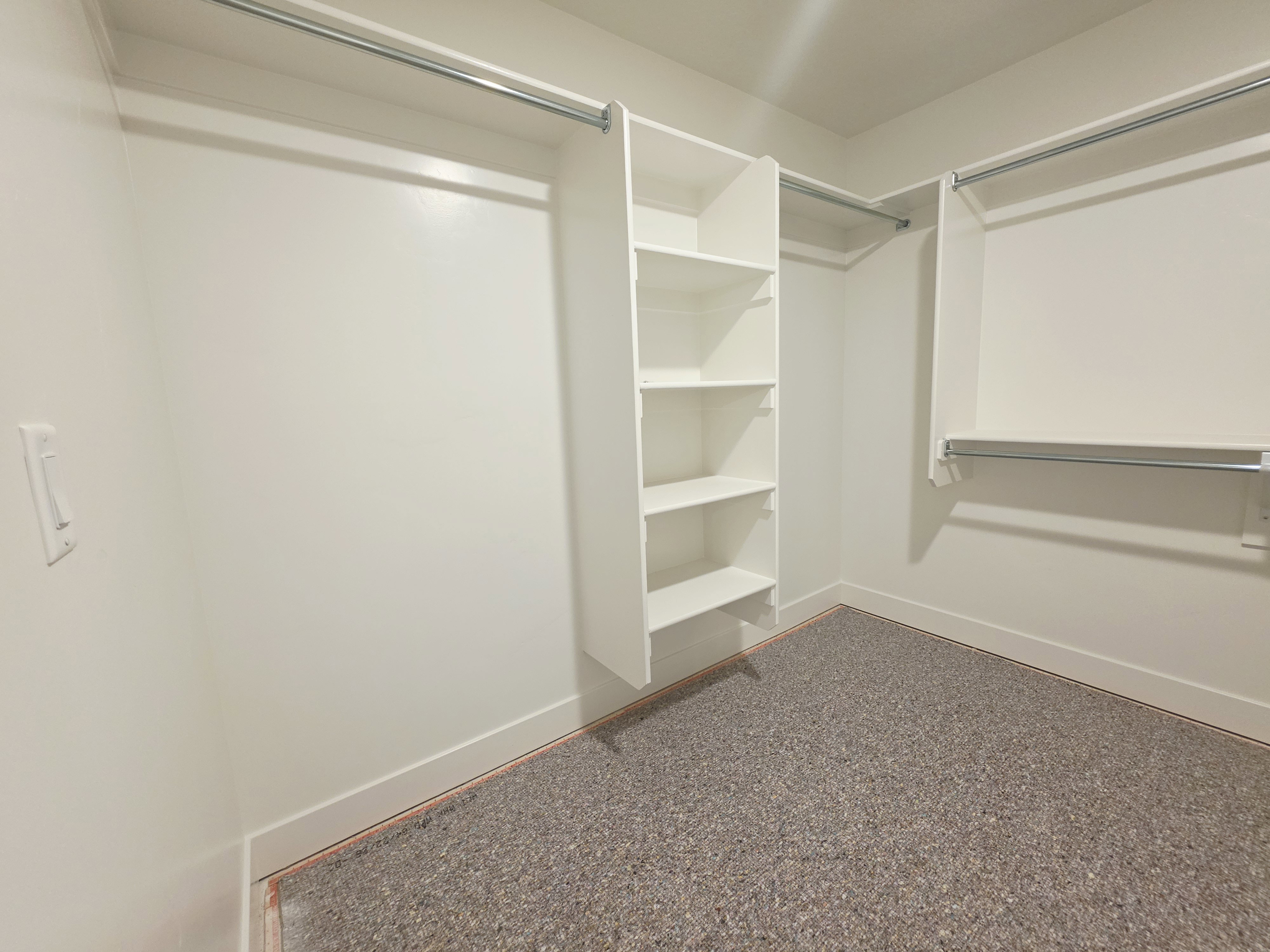 Walk-in closet featuring built-in shelving, dual hanging rods, and textured carpeting