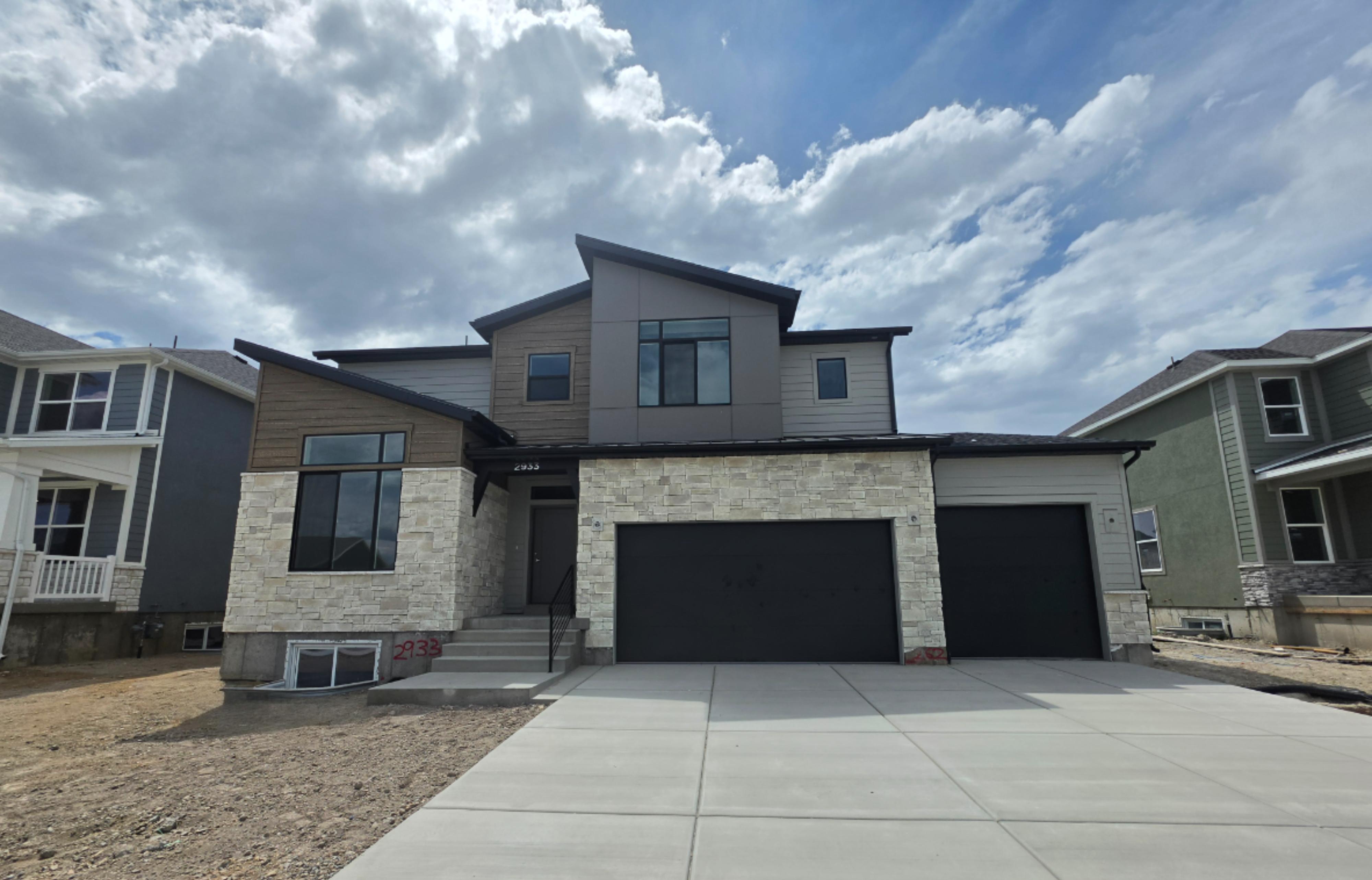 Modern architectural exterior featuring a combination of light-toned stone veneer, dark horizontal siding, and gray vertical panels