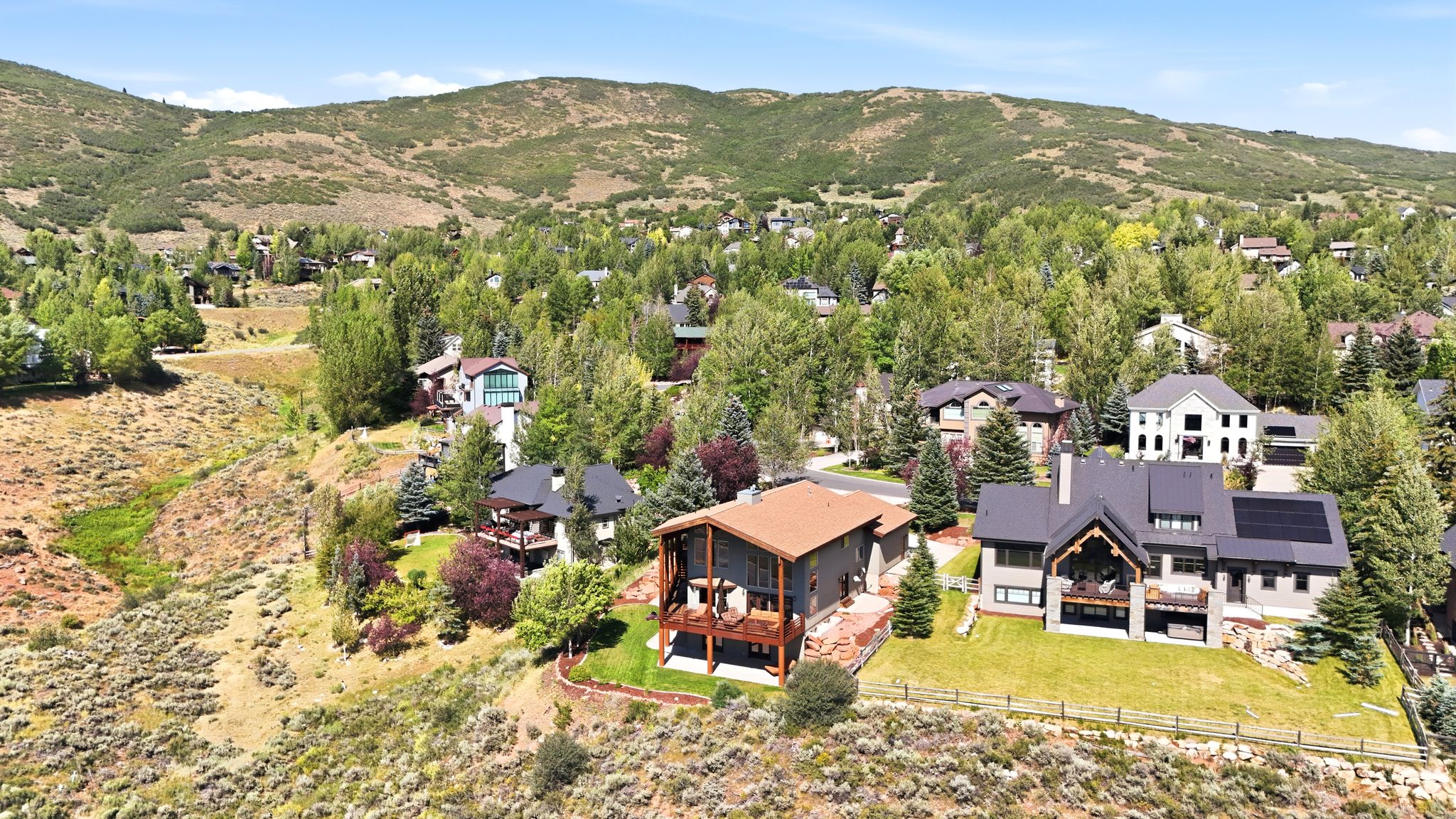 Modern multi-level residence featuring a dark gray roofline, integrated solar panels, and a prominent balcony