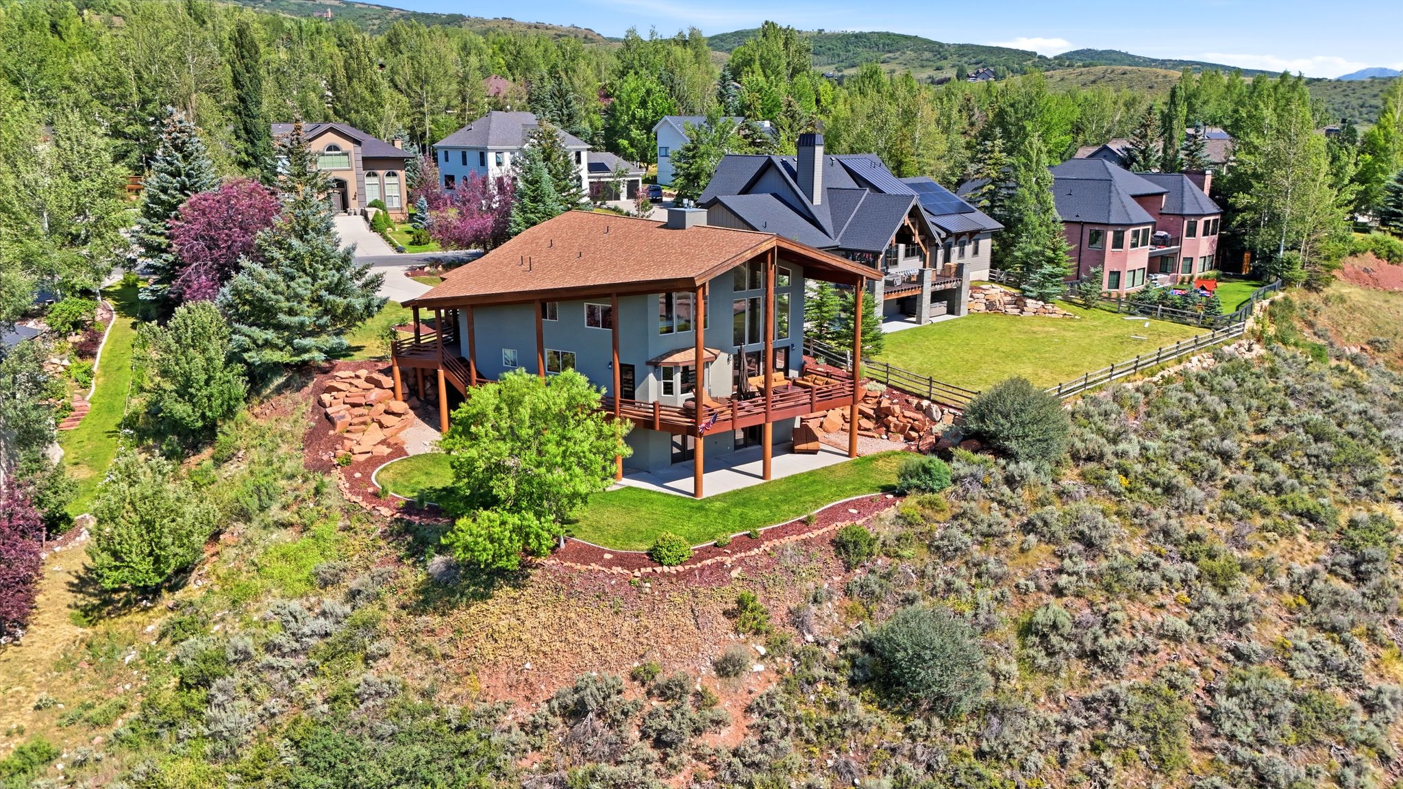 Multi-level residence featuring an expansive deck, light blue siding, and a brown shingle roof