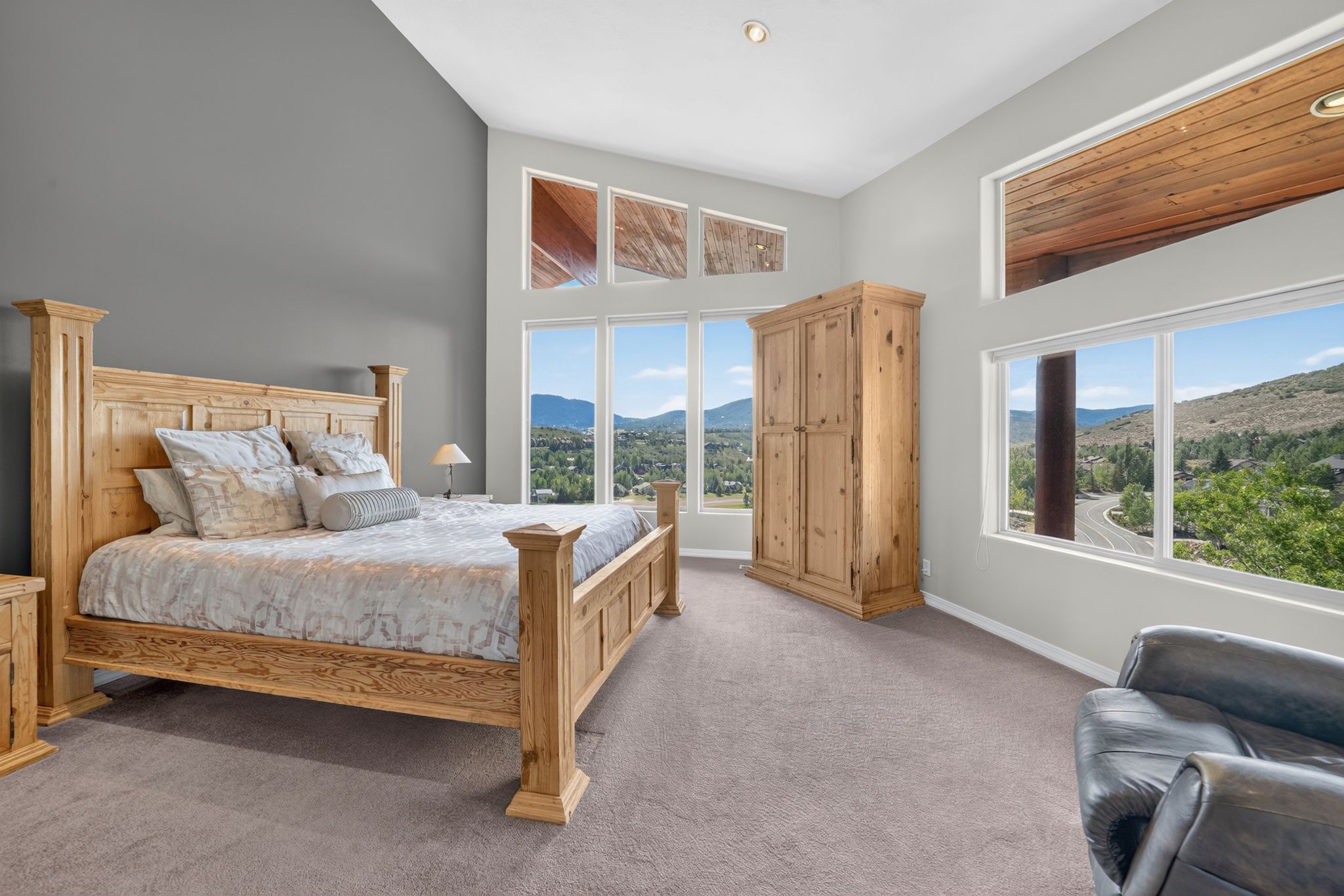 Room featuring an expansive window wall with transoms, vaulted ceiling, and recessed lighting