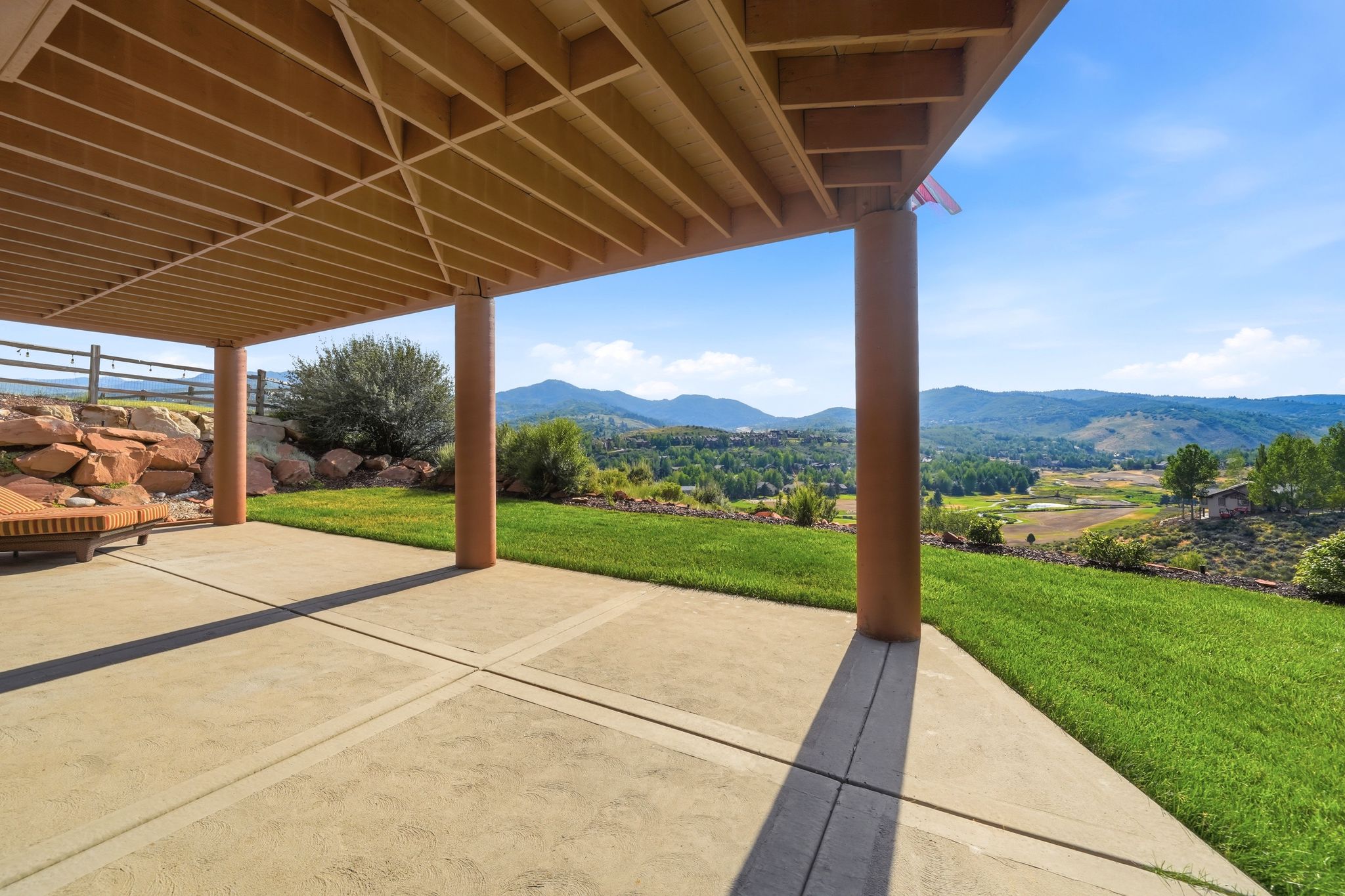 Expansive covered patio featuring a concrete surface and structural support columns