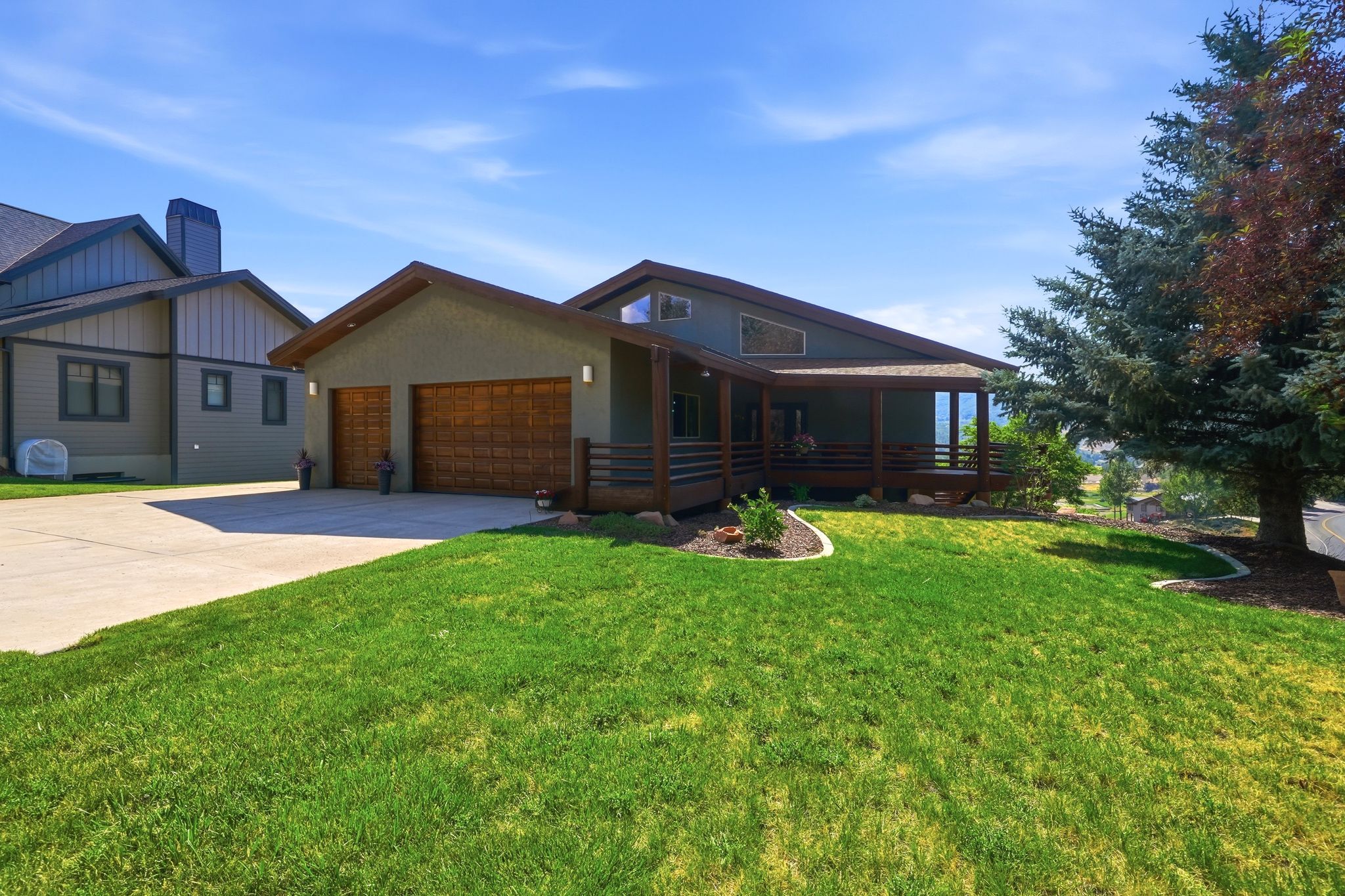 Modern-style residence featuring a sloped roofline, wood-finish garage doors, and a covered porch