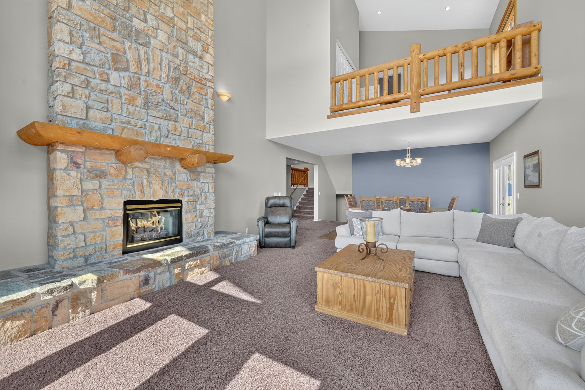 Spacious living area featuring a floor-to-ceiling stone fireplace with a substantial log mantel