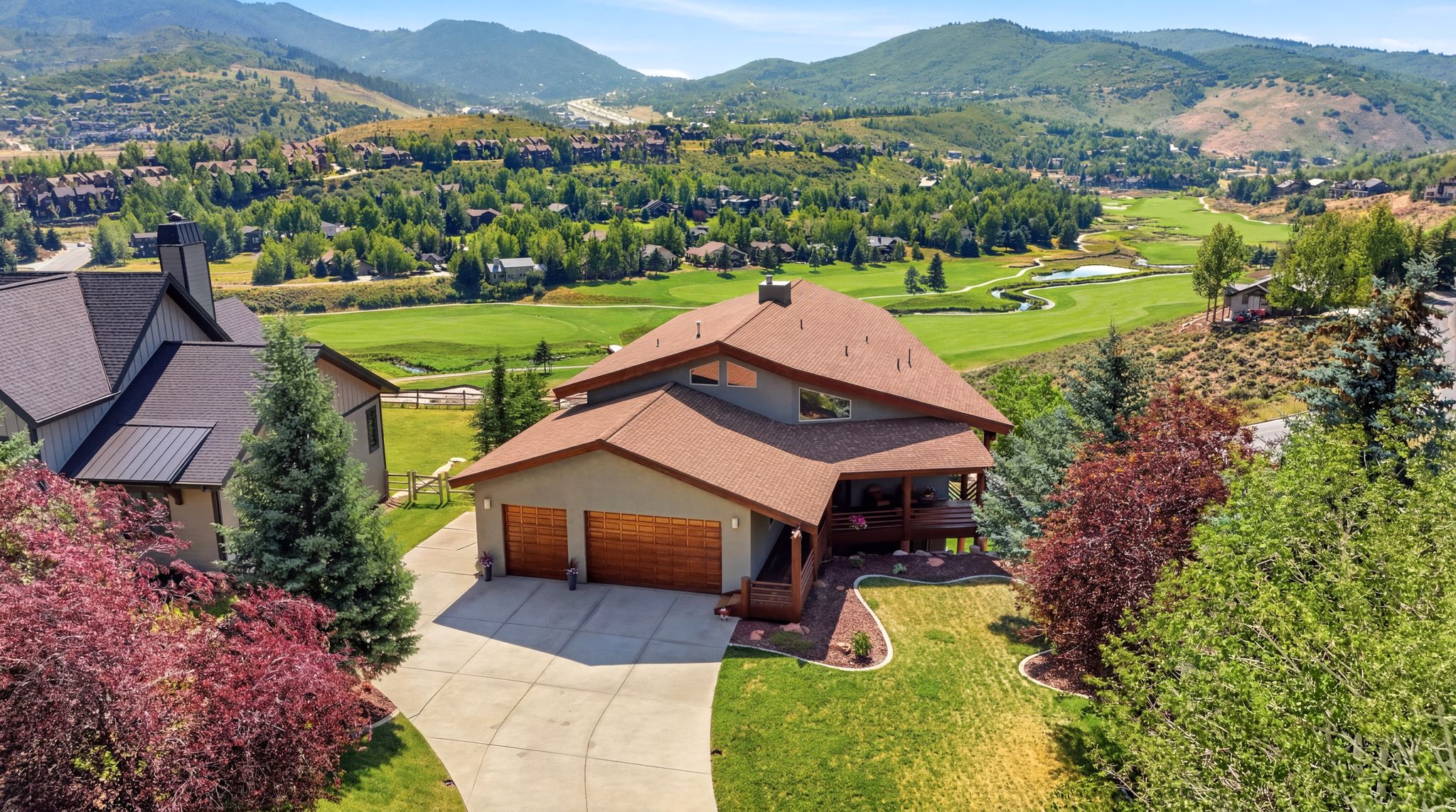 Expansive multi-level property with a brown shingle roof and integrated two-car garage featuring wood panel doors