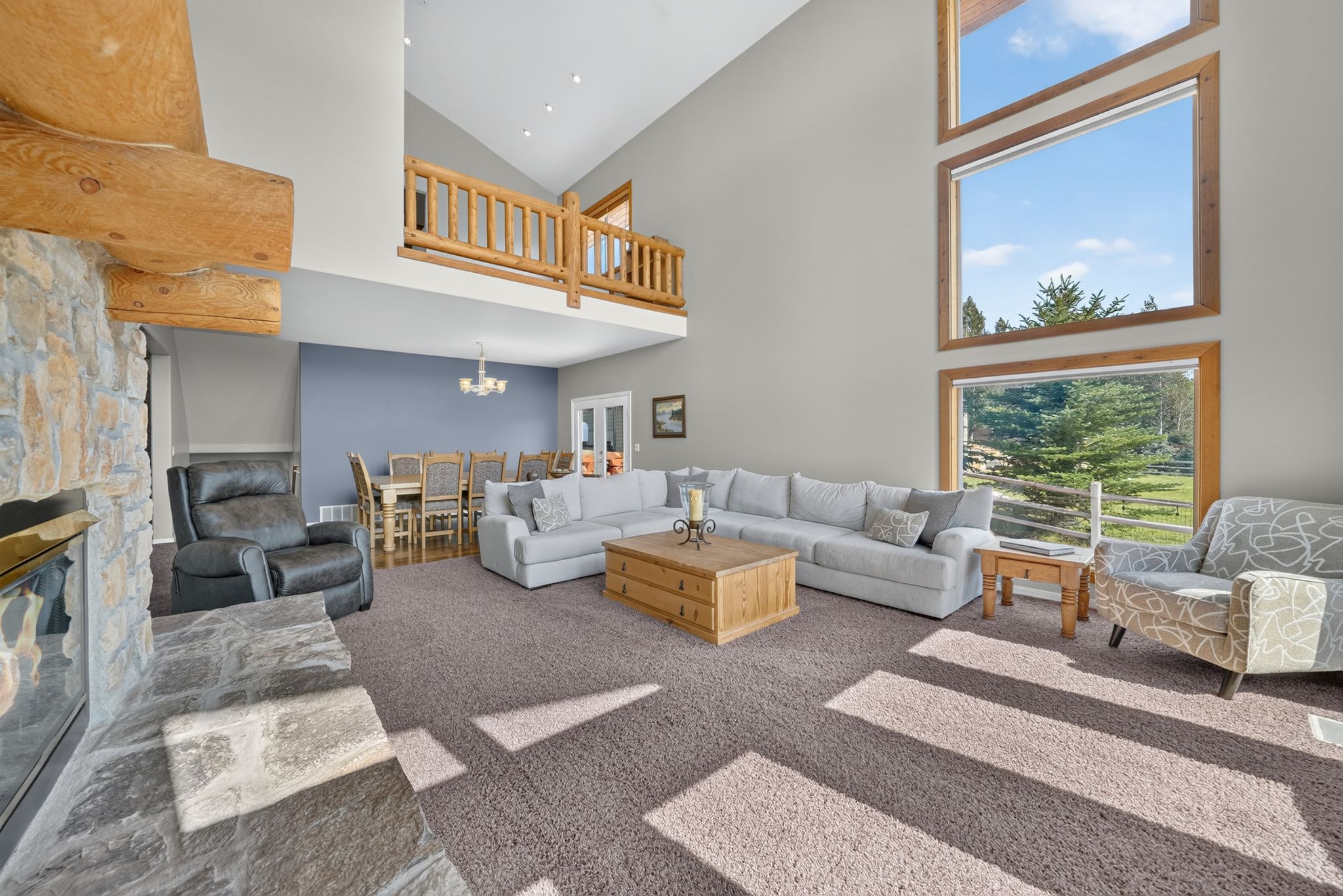 Great room featuring a vaulted ceiling and a stone-faced fireplace with a hearth