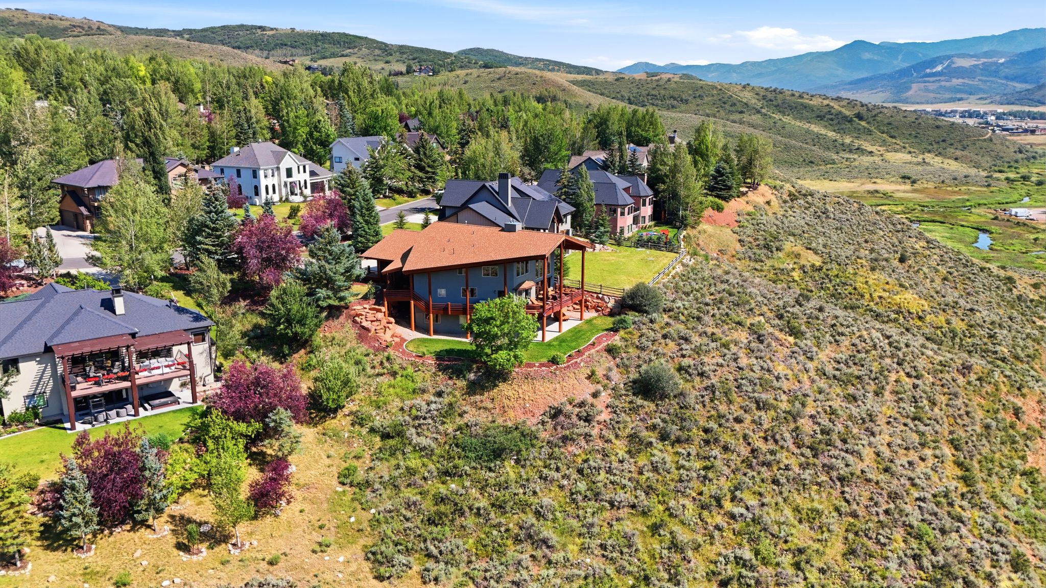 Contemporary home with a large deck, surrounded by mature trees and natural landscaping