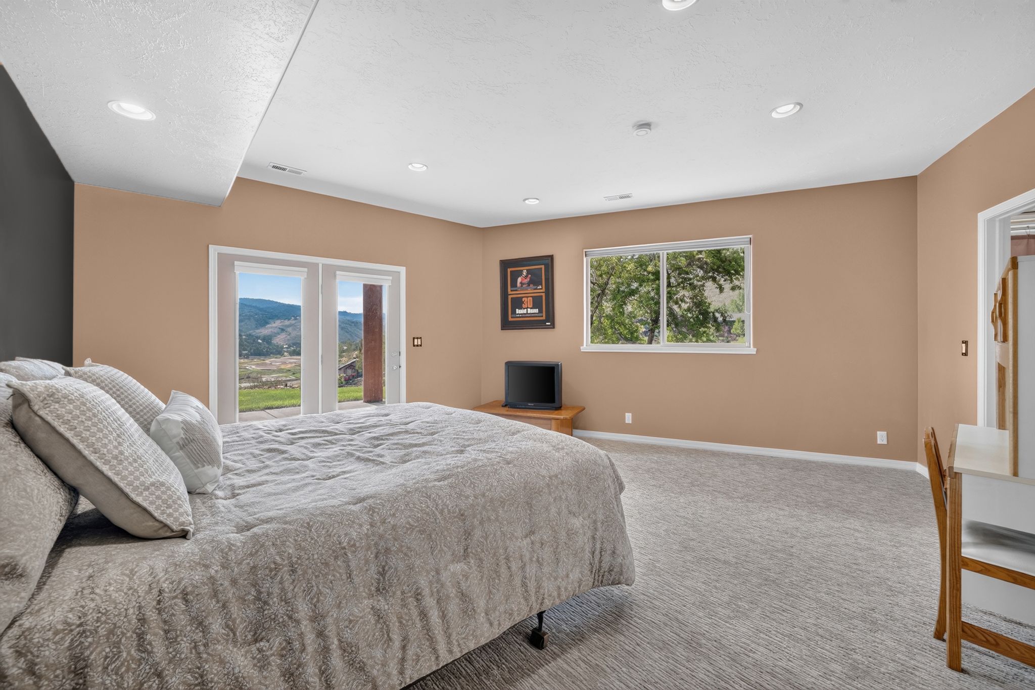 Bedroom featuring direct outdoor access through double French doors, recessed lighting, neutral tone walls, white trim, and patterned carpeting
