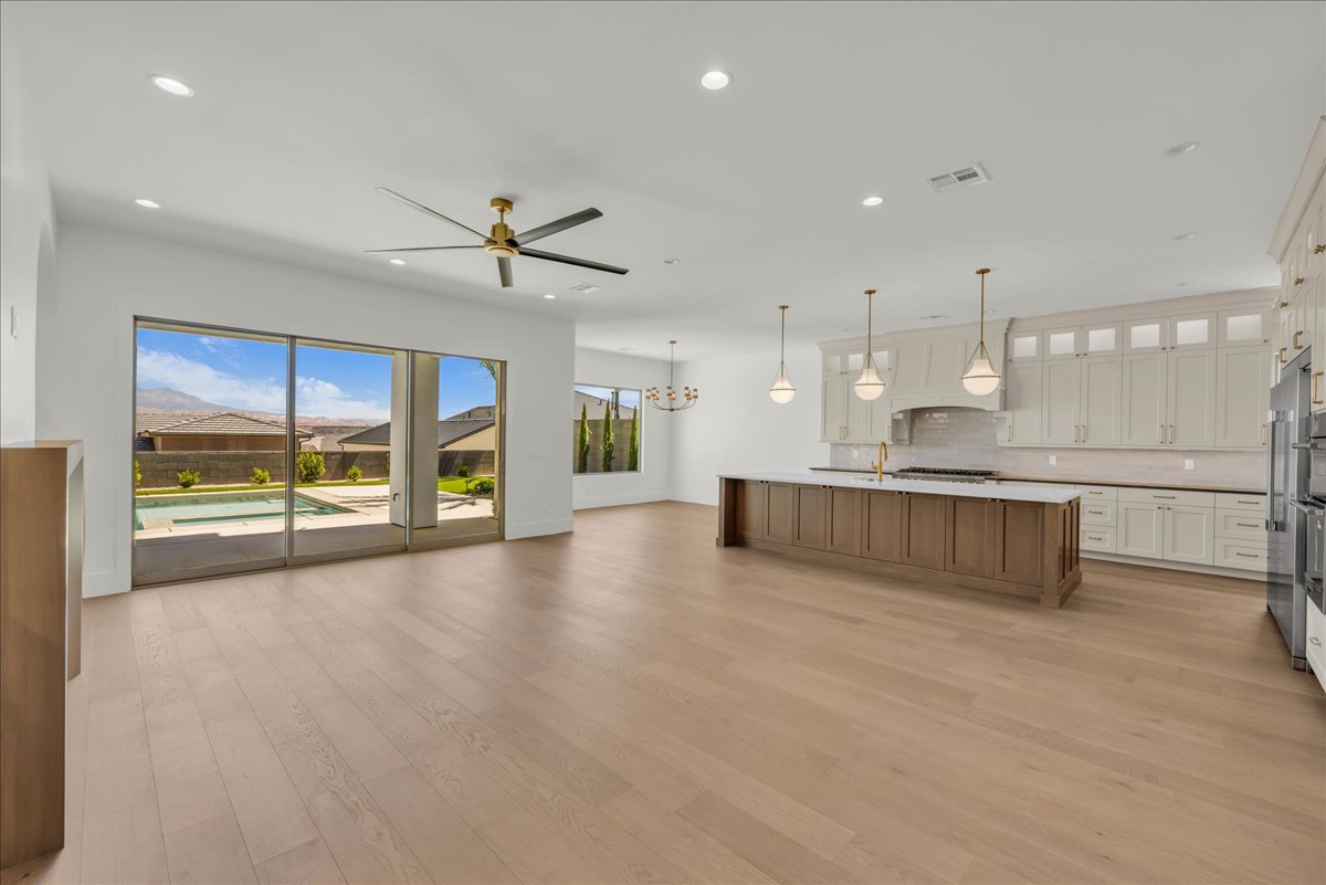 Open-concept living area with wood-finish flooring, a contemporary ceiling fan, and sliding glass doors leading to a private pool