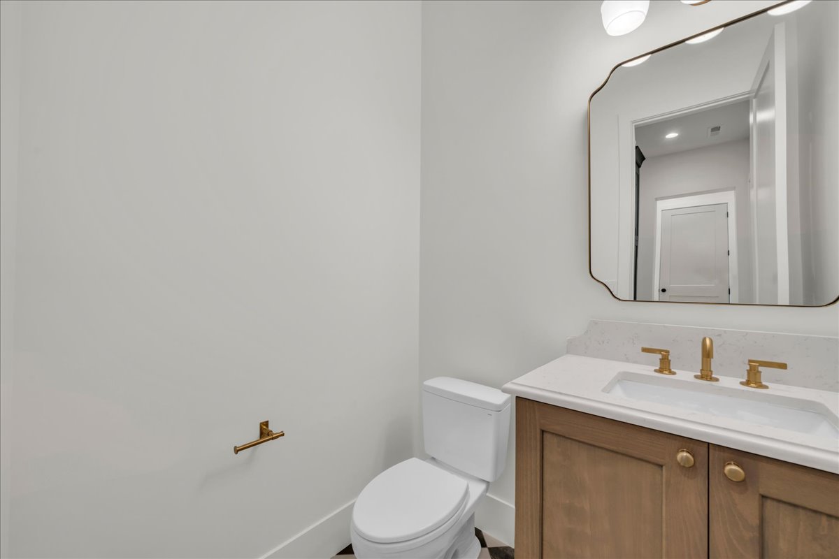 Bathroom vanity featuring a light wood-finish cabinet with gold-toned hardware, an integrated sink with a light-toned countertop, and a matching gold-toned faucet