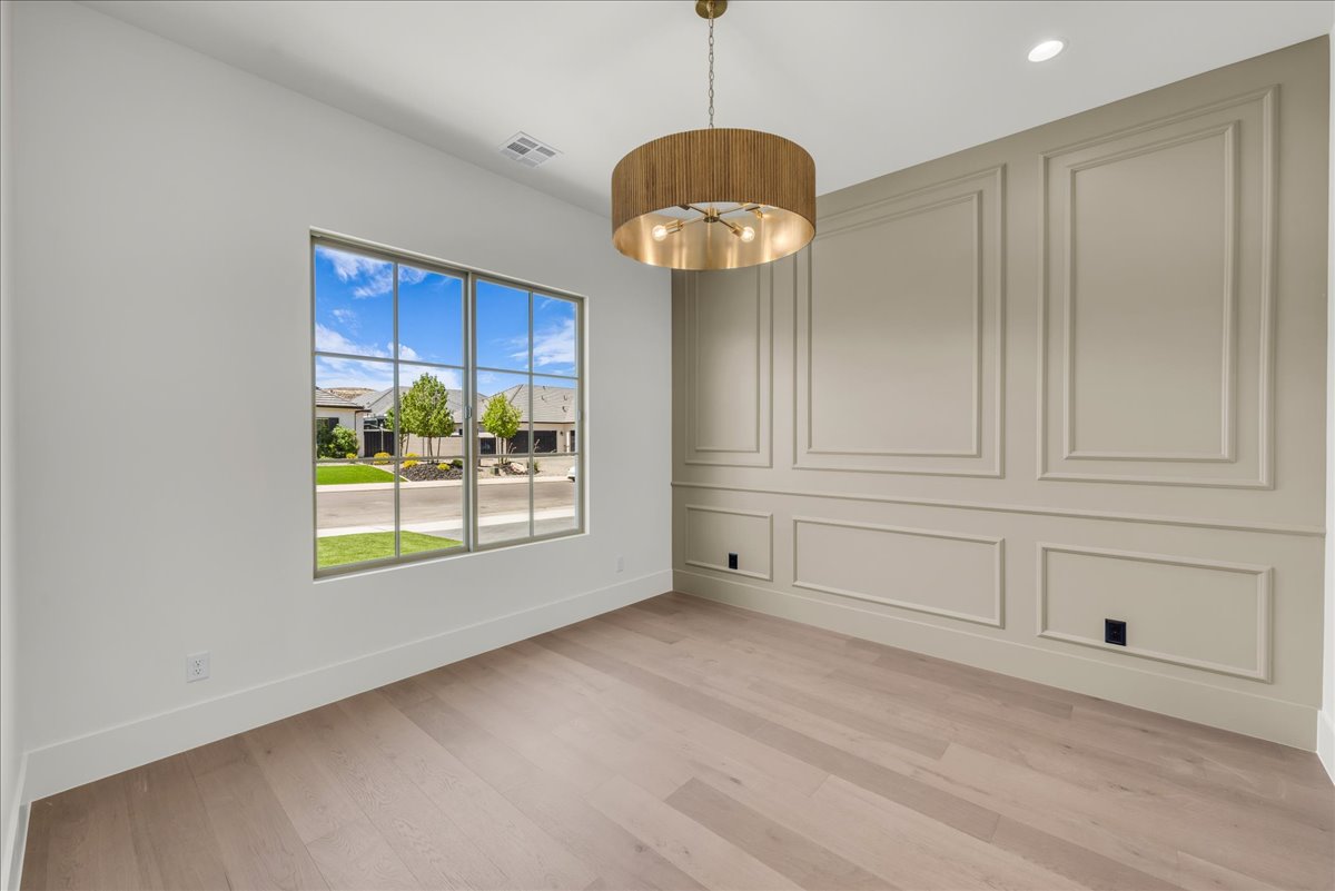 Room featuring light wood-finish flooring, a large multi-pane window, and a decorative accent wall with panel molding