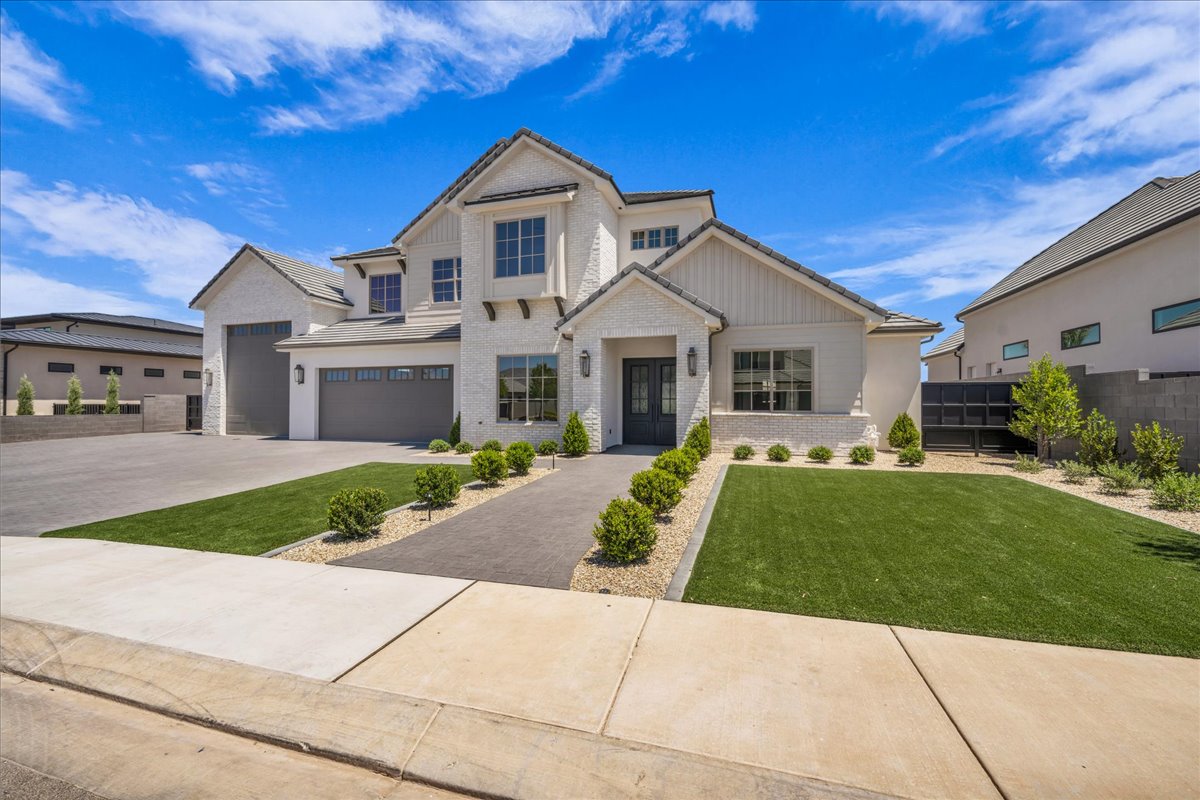 White brick and stucco exterior featuring multiple gables and dark-framed windows