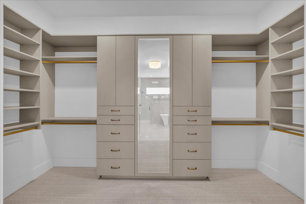 Custom closet system featuring built-in cabinetry, shelving, hanging rods, and a mirrored panel