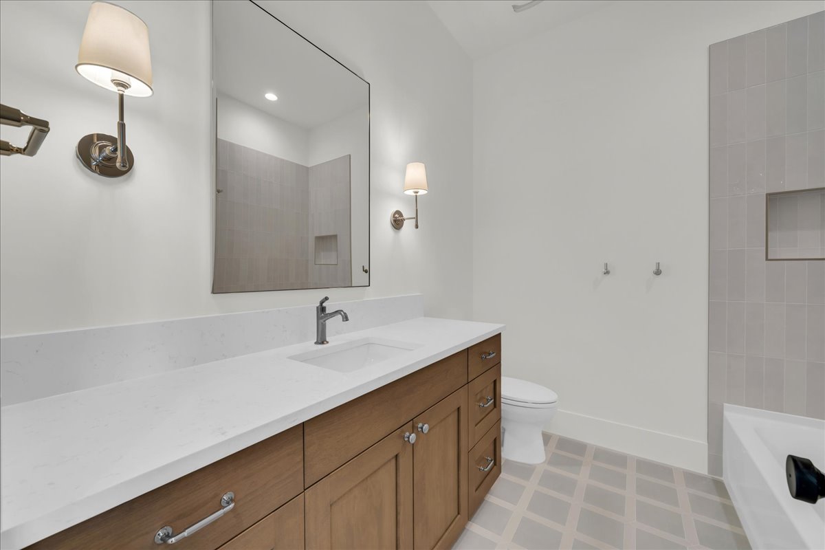White solid surface countertop with integrated sink, wood-finish vanity cabinetry, and brushed nickel hardware