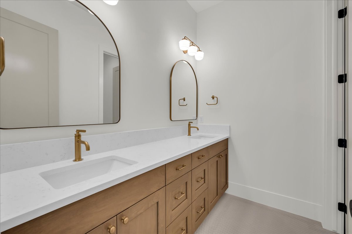 Dual vanity featuring a wood-finish cabinet, white countertop, and gold-finish fixtures