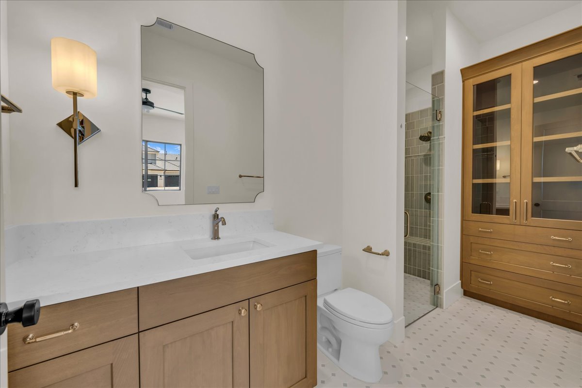 Bathroom featuring a wood-finish vanity with a light-toned countertop and integrated sink, a framed mirror, and a wall-mounted light fixture