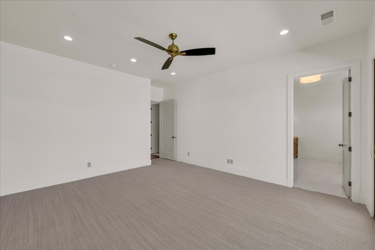 Spacious room featuring neutral carpeting, recessed lighting, a ceiling fan with gold-tone accents, and white trim