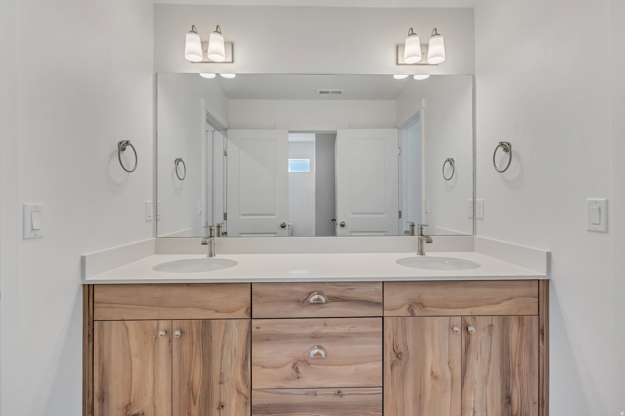 Dual vanity with wood-finish cabinetry, white countertop, and integrated sinks
