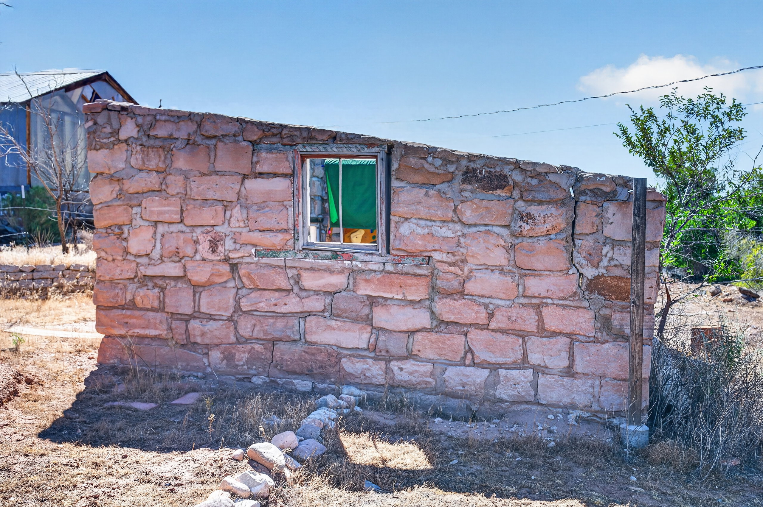 Stone wall structure featuring a window opening and surrounding natural vegetation