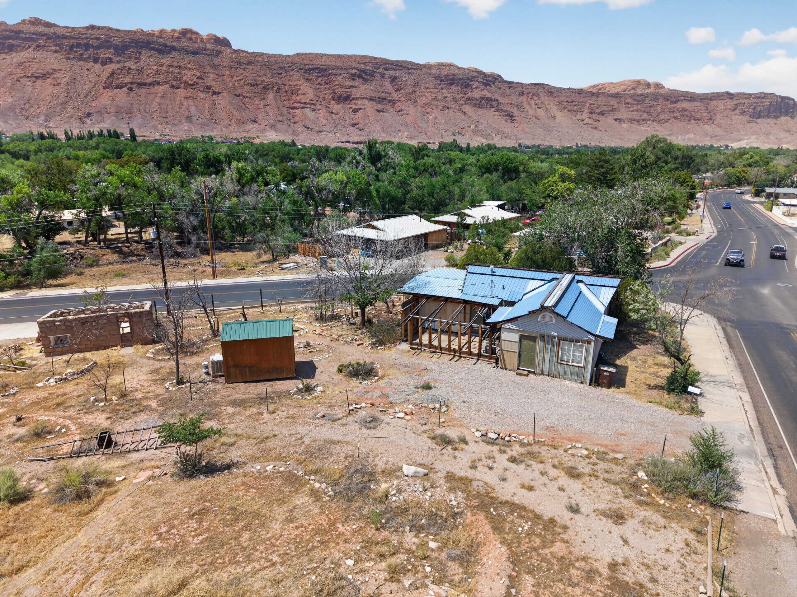 Property featuring a blue metal roof, gravel driveway, and an adjacent paved road