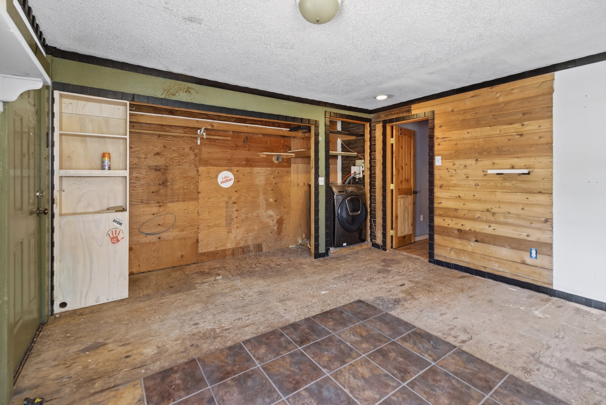 Room featuring partial wood-plank accent wall and tile flooring