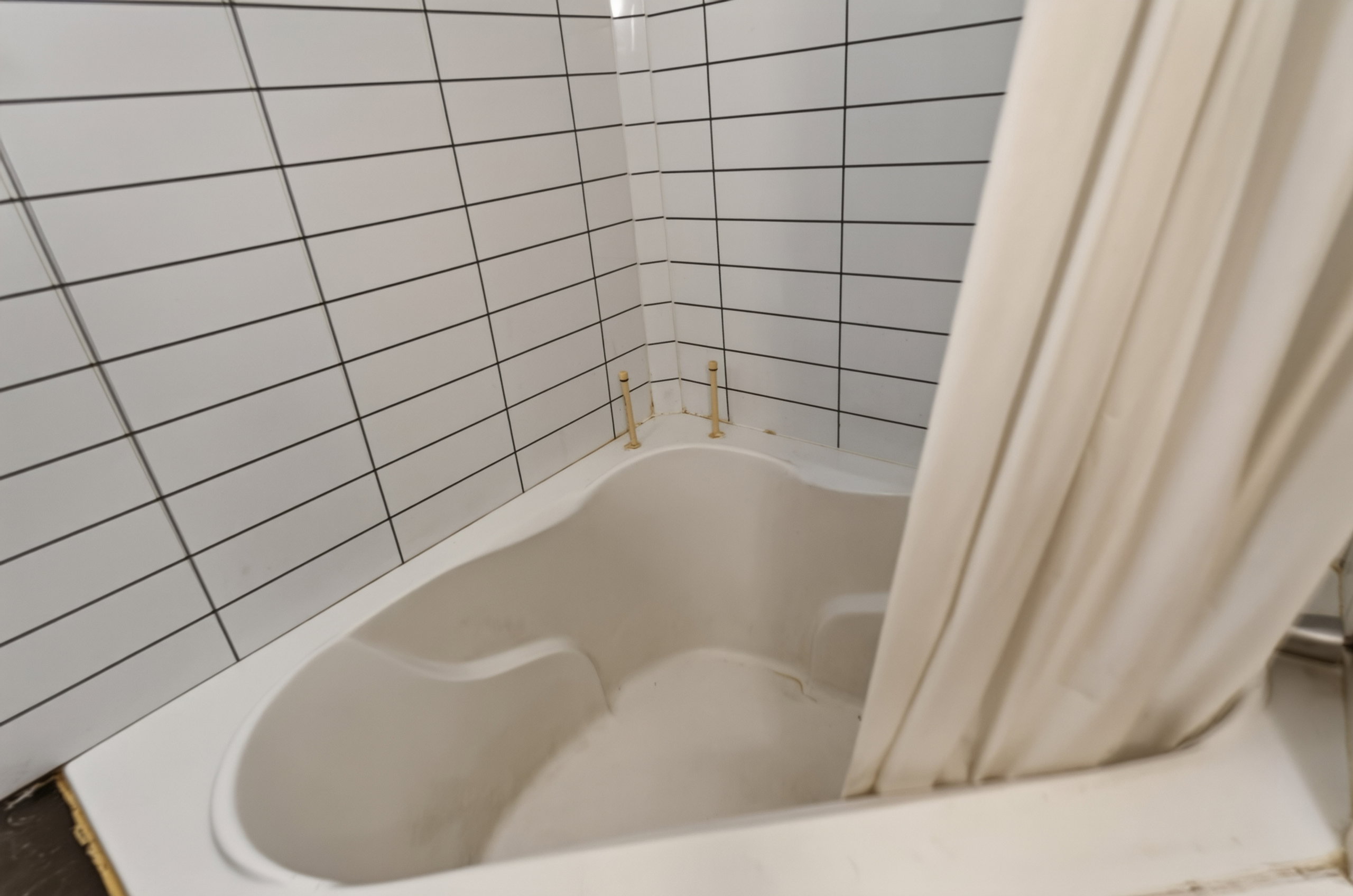 Corner tub with white subway tile surround and brass fixtures