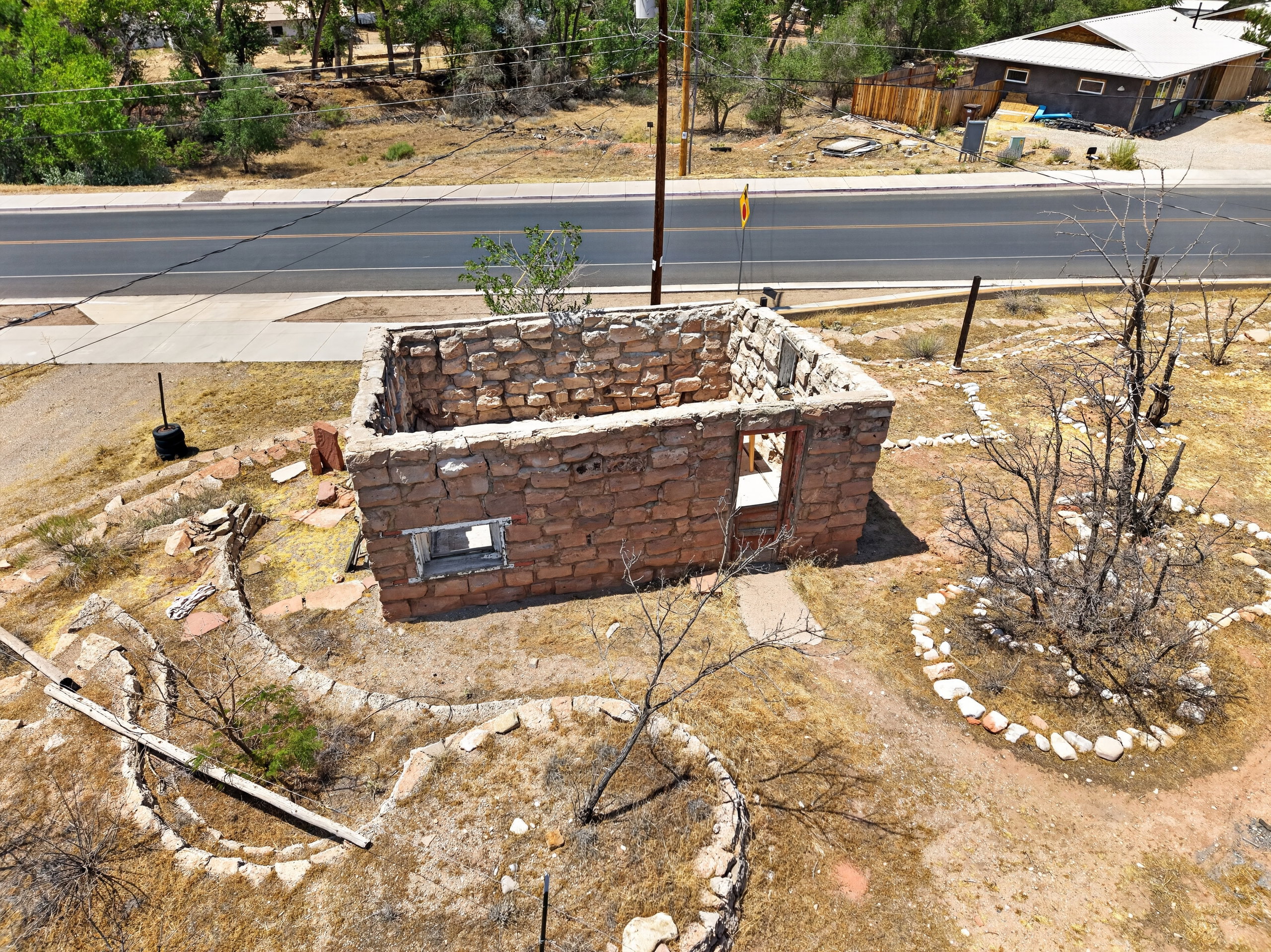 Stone structure with open window and door frames, surrounded by dry landscaping