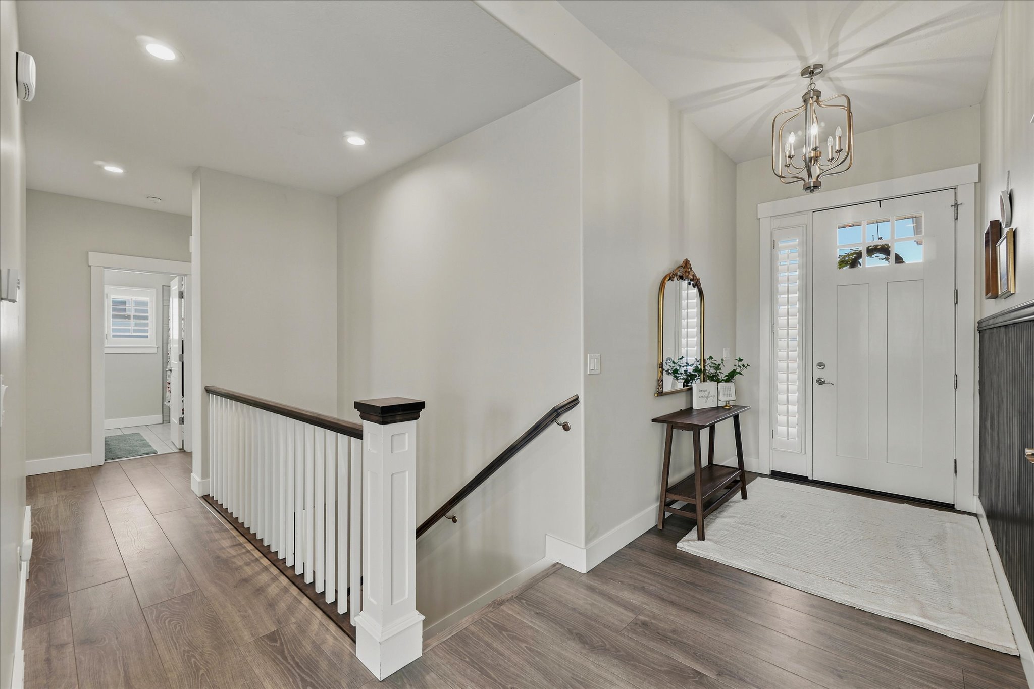 Entryway featuring a white paneled door with sidelights, wood-finish flooring, recessed lighting, and a chandelier
