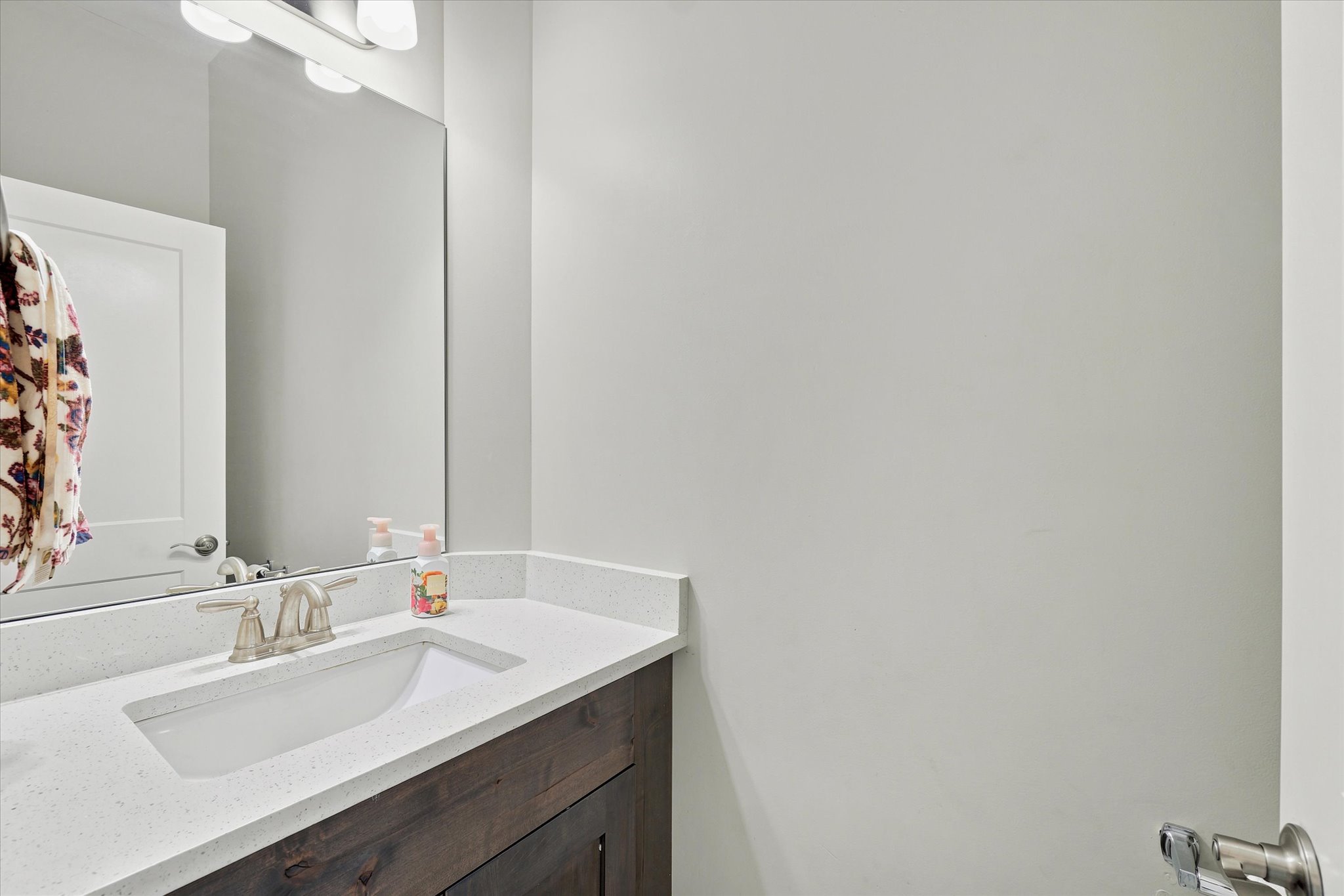 Bathroom vanity with a white rectangular undermount sink, brushed nickel faucet, and a light-toned countertop