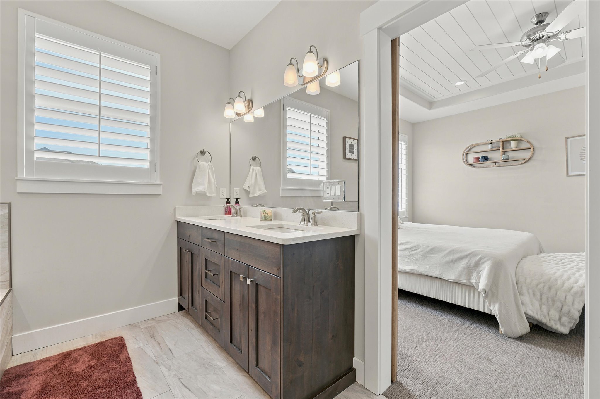 Bathroom featuring a double vanity with dark wood cabinetry, white countertops, dual undermount sinks, and polished chrome fixtures