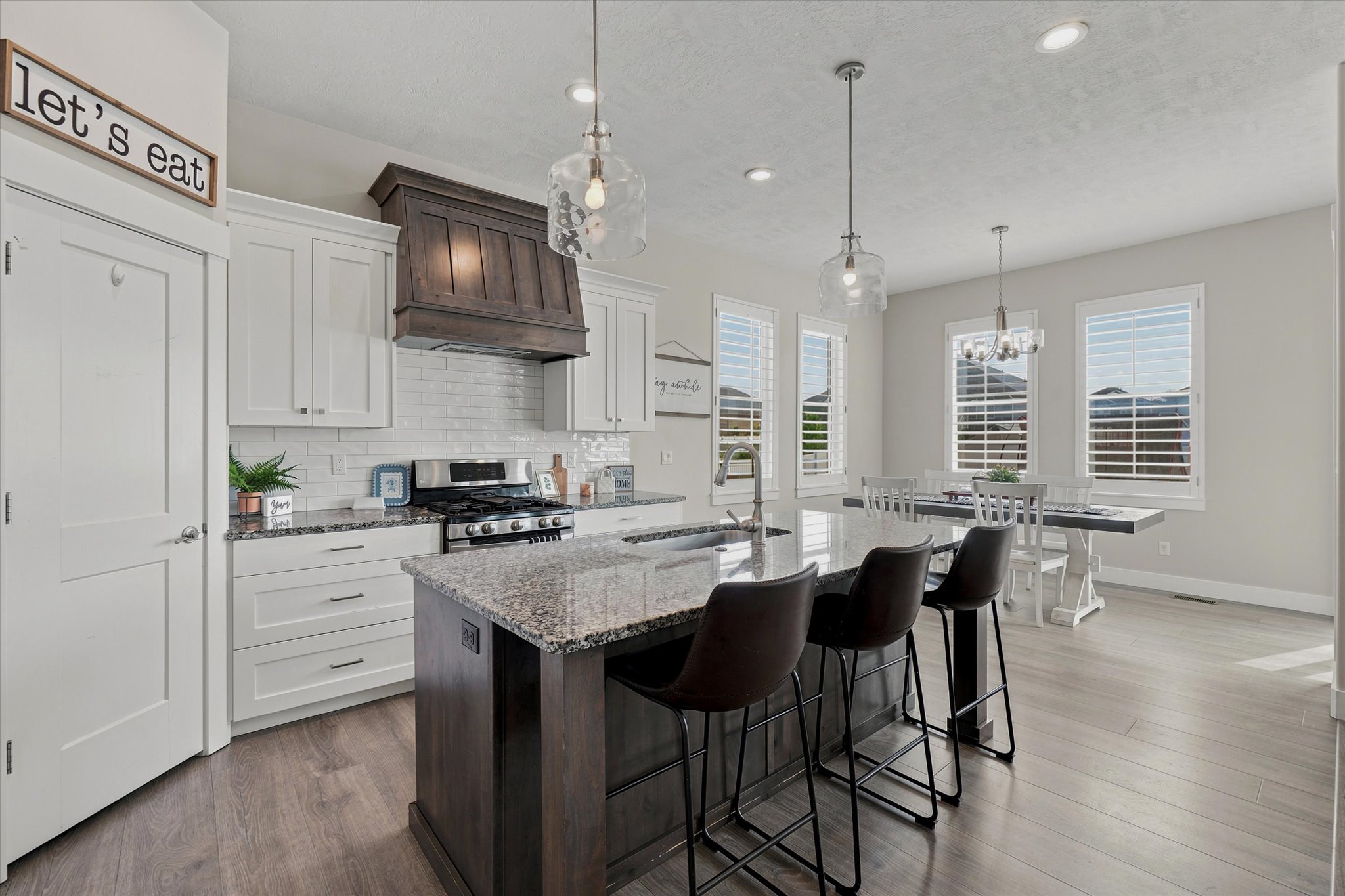 Open-concept kitchen featuring white shaker cabinetry, stainless steel appliances, and wood-finish flooring