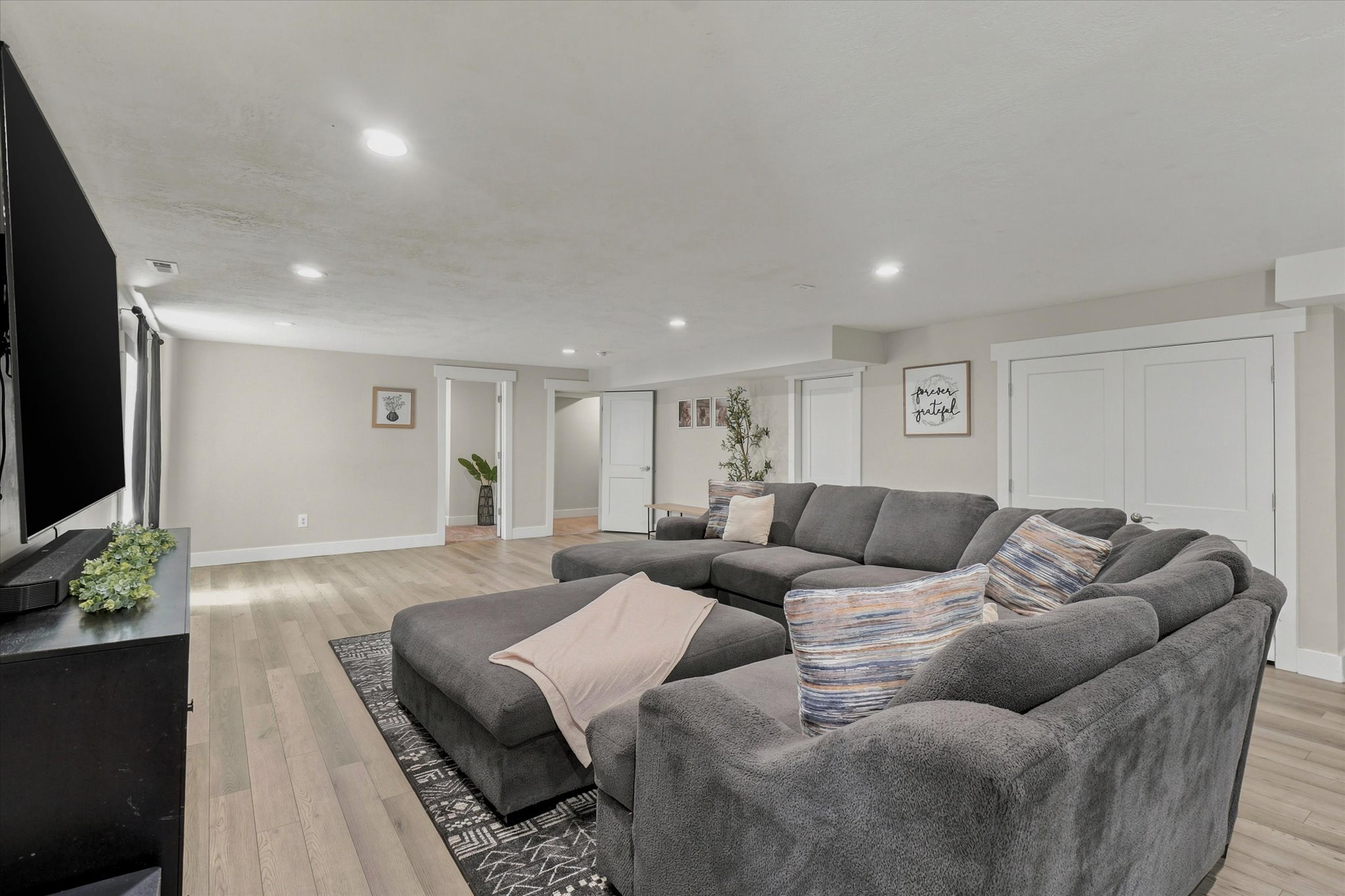 Spacious living area featuring light wood-finish flooring, recessed lighting, and neutral wall tones