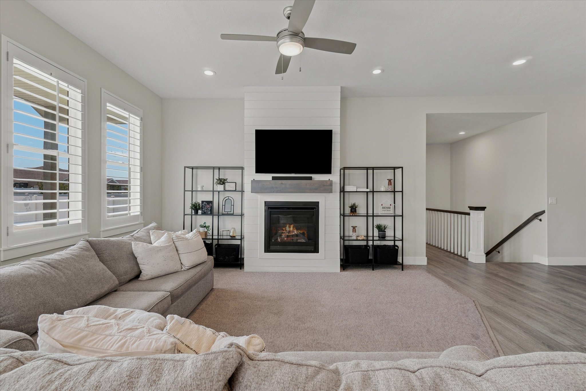 Living area featuring a fireplace with shiplap surround, a wood-finish mantel, and a ceiling fan