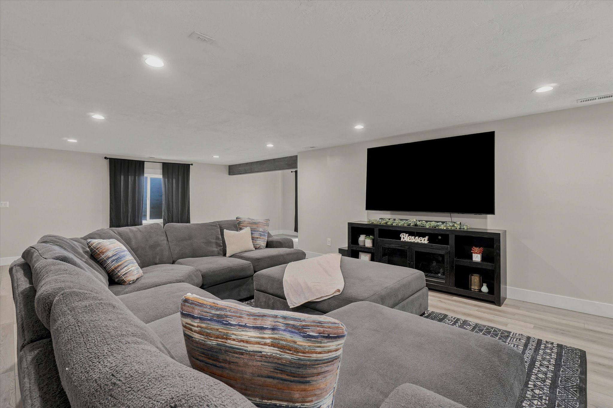 Spacious room featuring recessed lighting, light-toned walls, and wood-finish flooring