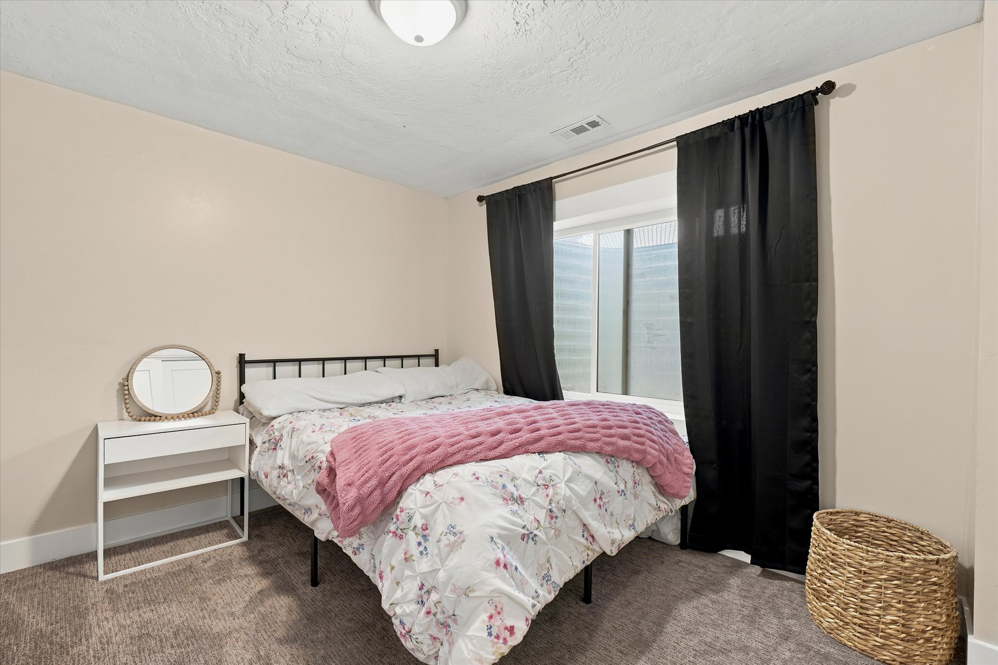 Carpeted room featuring a window with dark drapery, light-colored walls, and a flush-mount ceiling light fixture