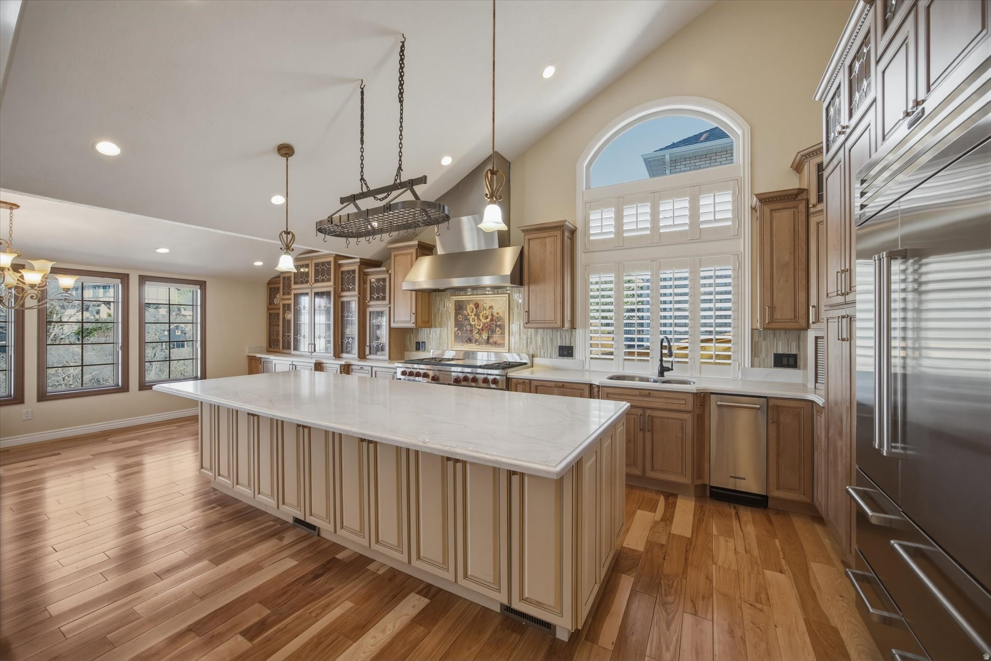 Kitchen featuring an expansive center island with a light-toned countertop, stainless steel appliances, abundant cabinetry, and wood-finish flooring