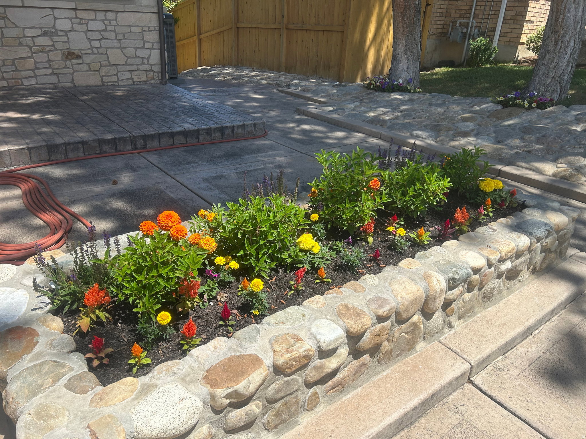 Stone-faced raised garden bed featuring a variety of colorful plantings