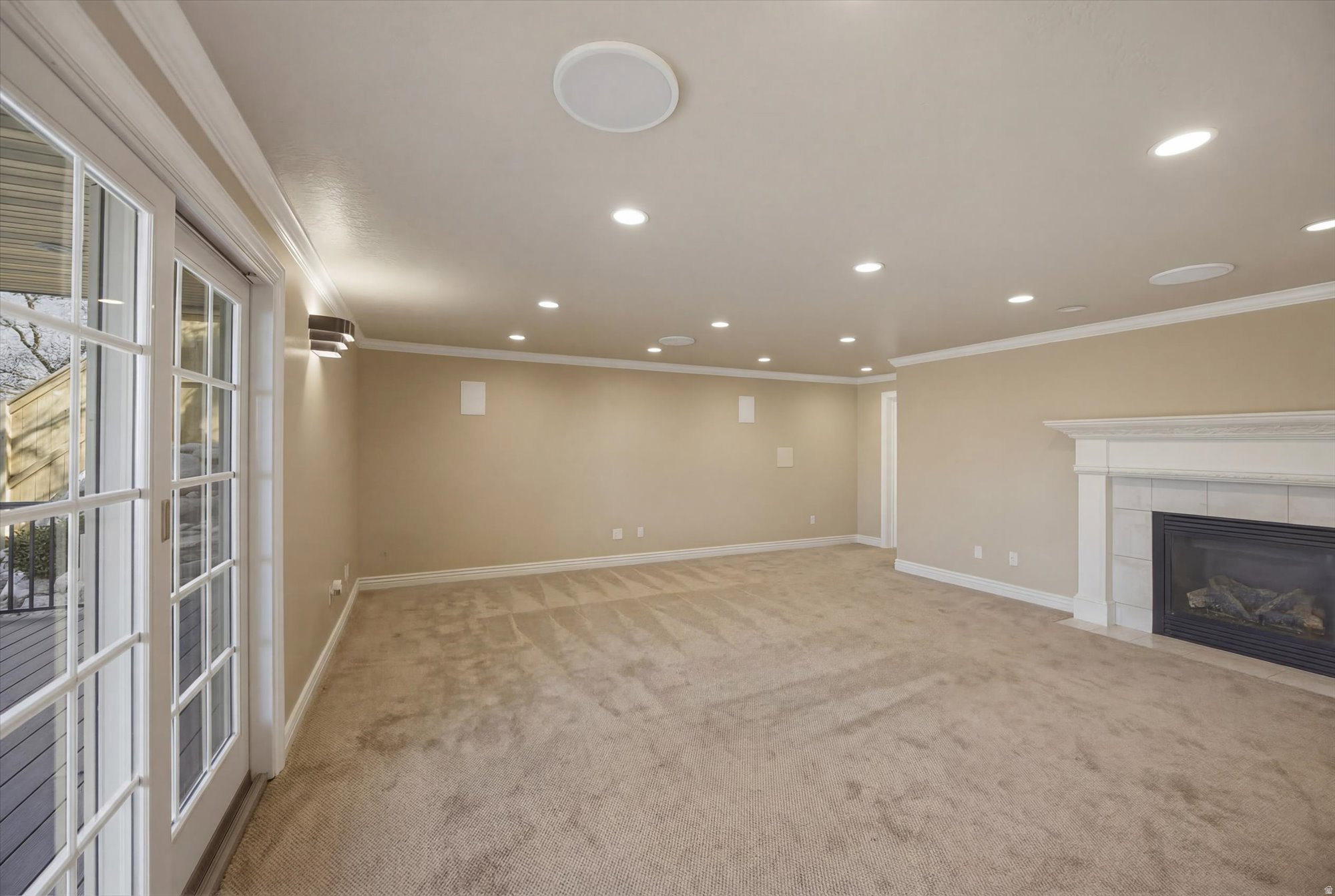 Spacious interior featuring a gas fireplace with a white mantel, recessed lighting, crown molding, and light-toned carpeting