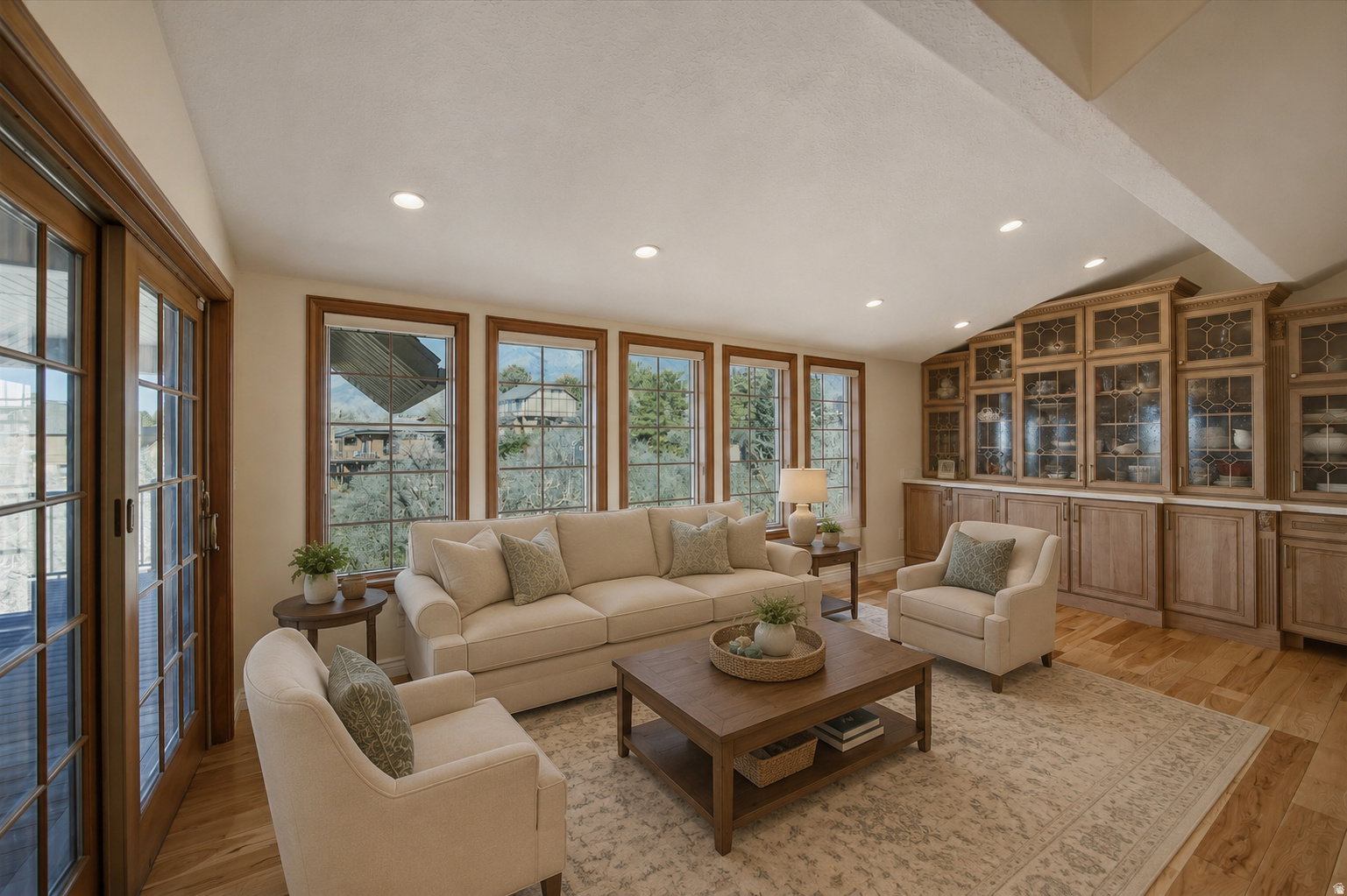 Living area featuring light wood flooring and extensive built-in cabinetry with glass-front uppers