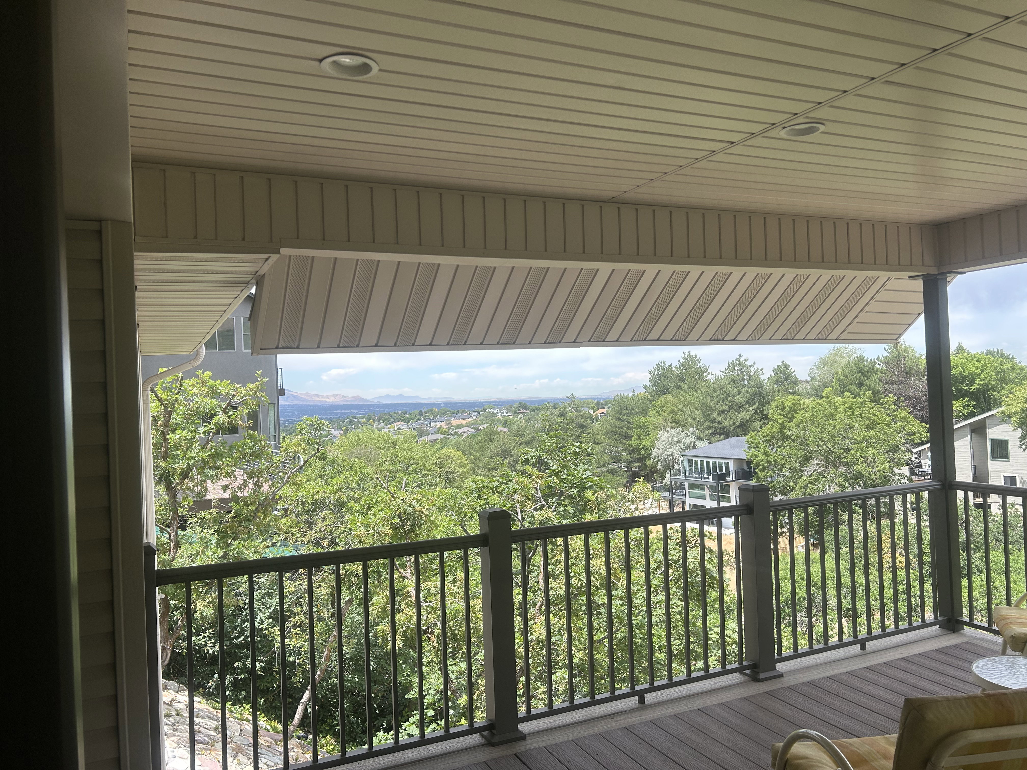 Covered outdoor deck featuring composite decking, recessed lighting, and a metal railing system