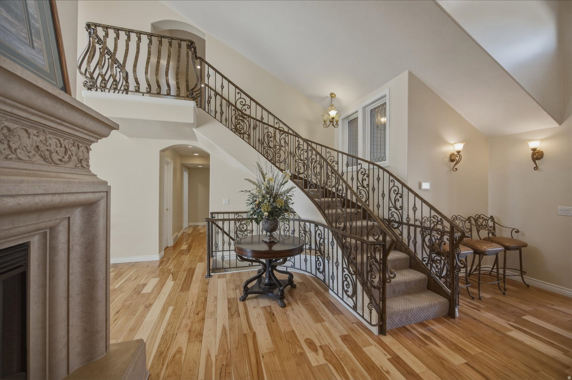 Curved staircase featuring ornate wrought iron railings, carpeted treads, and wood-finish flooring