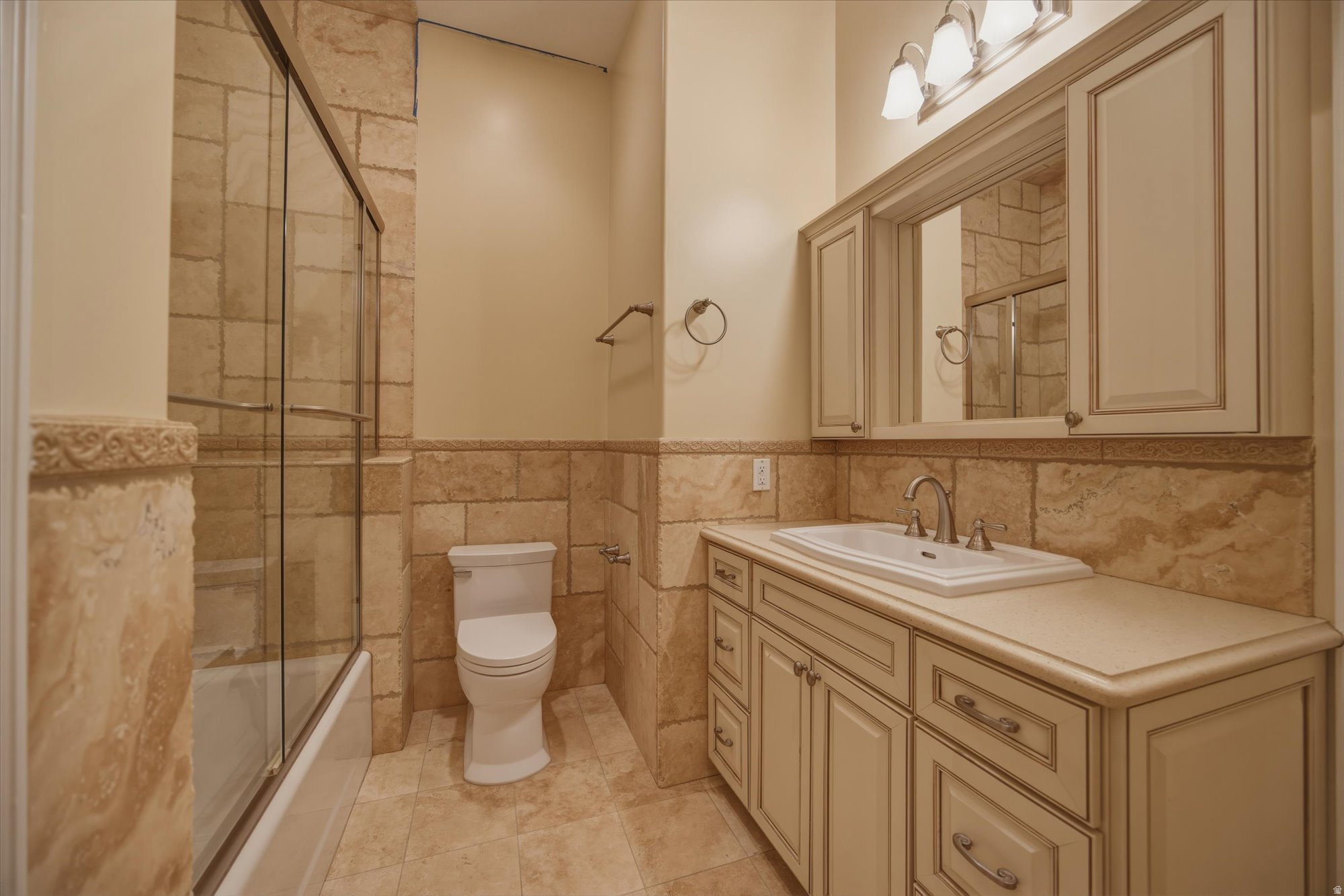 Full bathroom featuring a single vanity with extensive cabinetry, an integrated sink, and a framed mirror