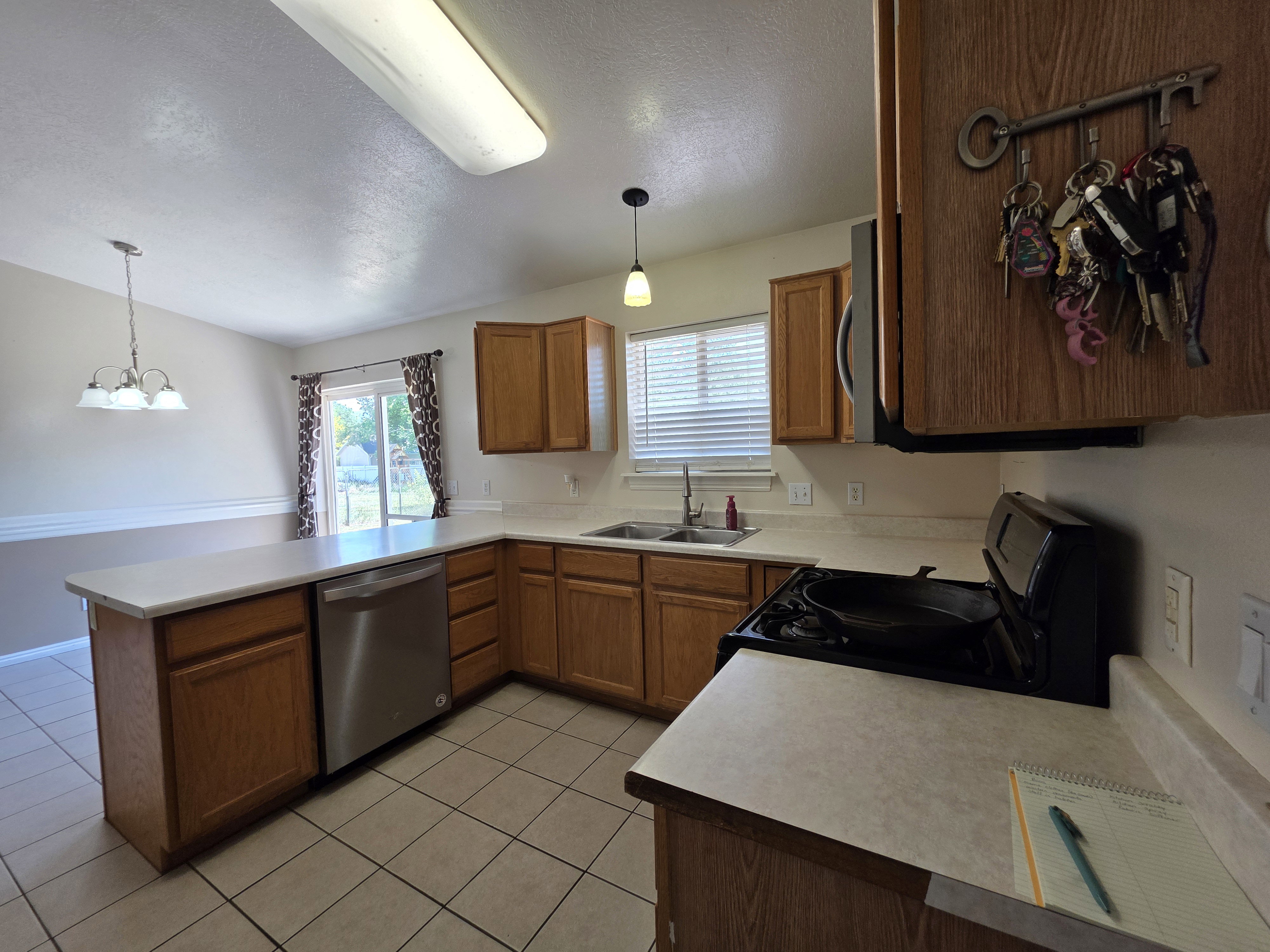 Kitchen featuring wood-finish cabinetry, tile flooring, light-toned countertops, and a stainless steel dishwasher