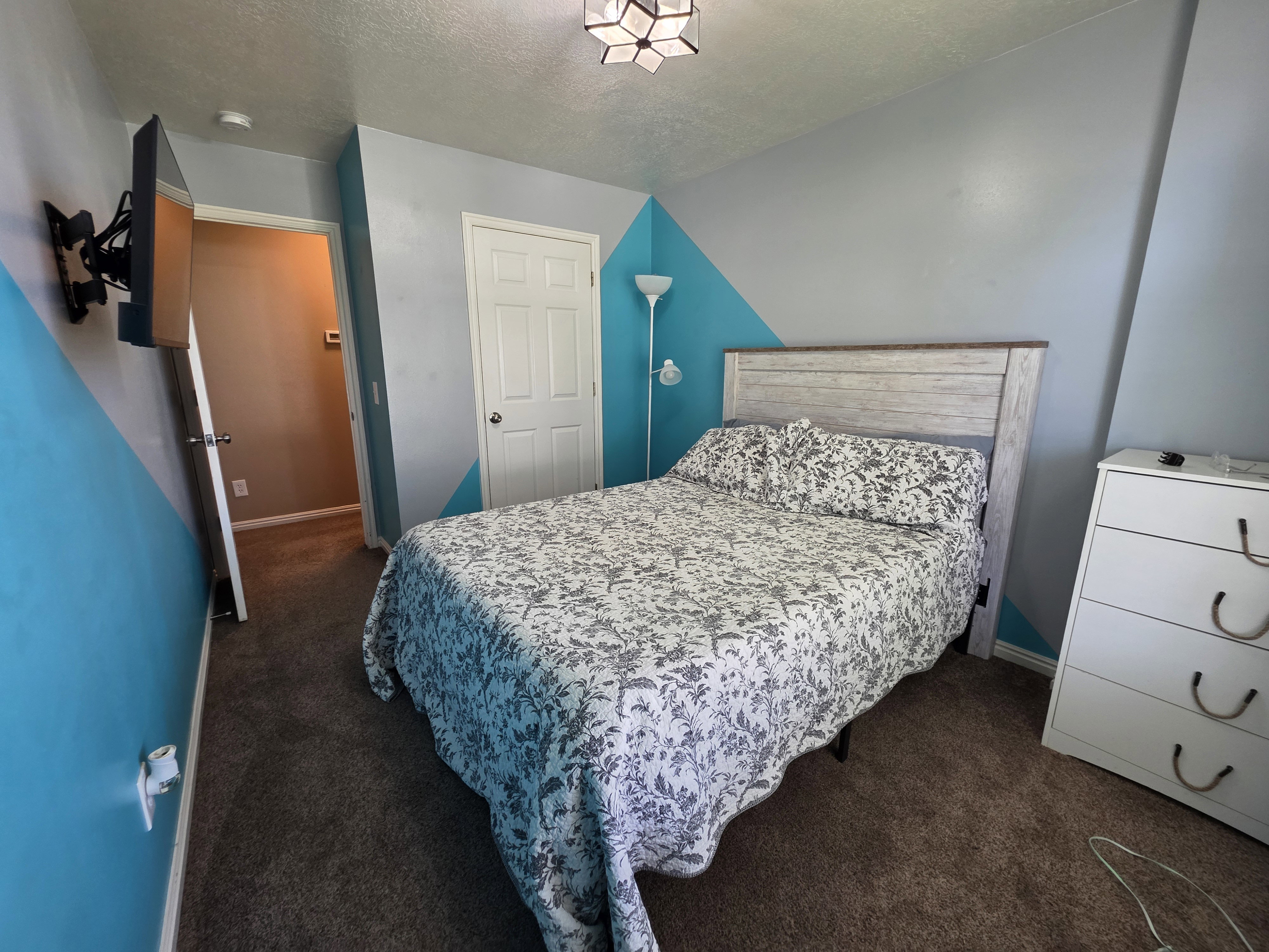 Carpeted bedroom featuring a textured gray and blue accent wall