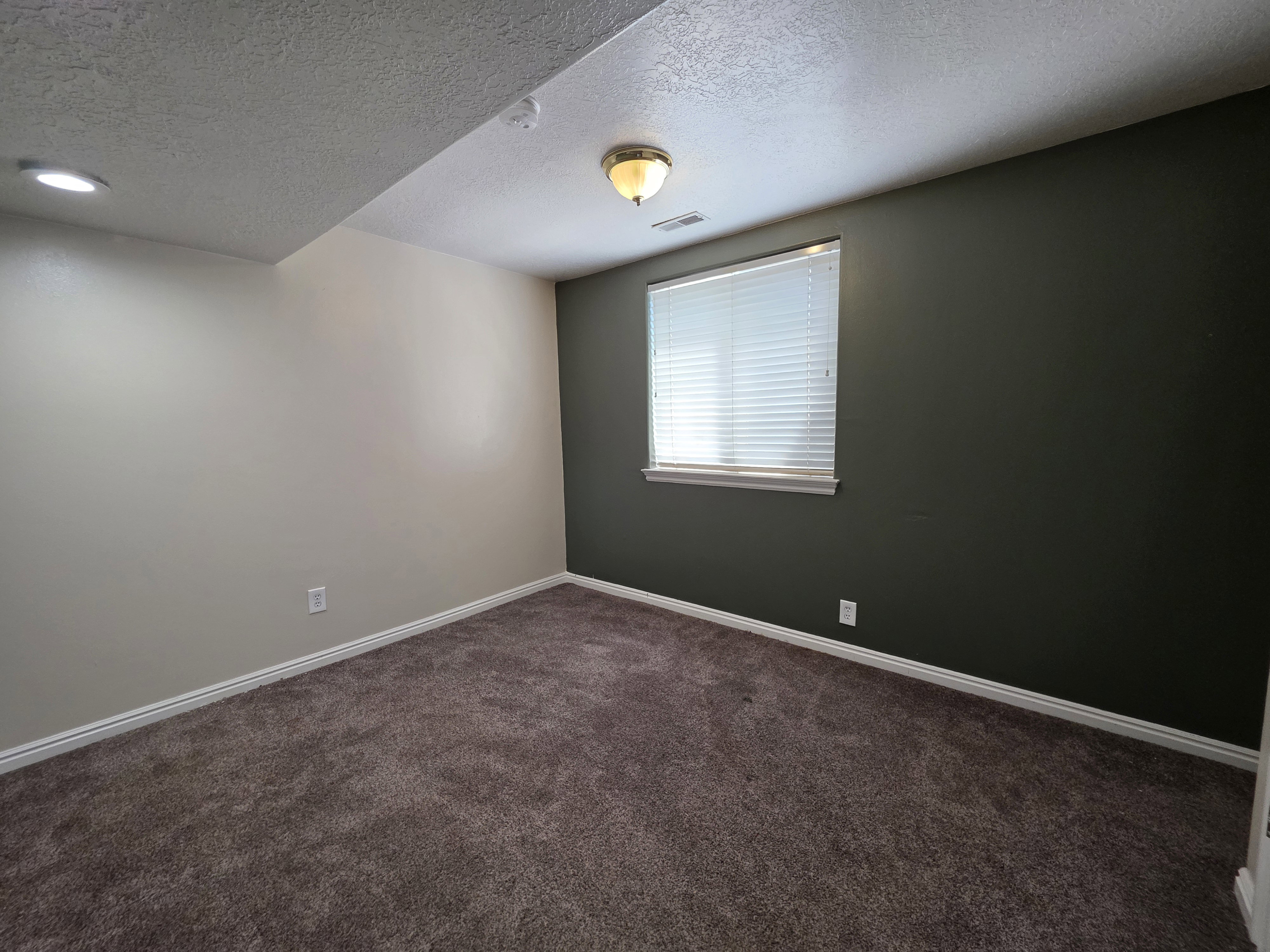 Carpeted room featuring a window with blinds, recessed lighting, and a ceiling-mounted fixture