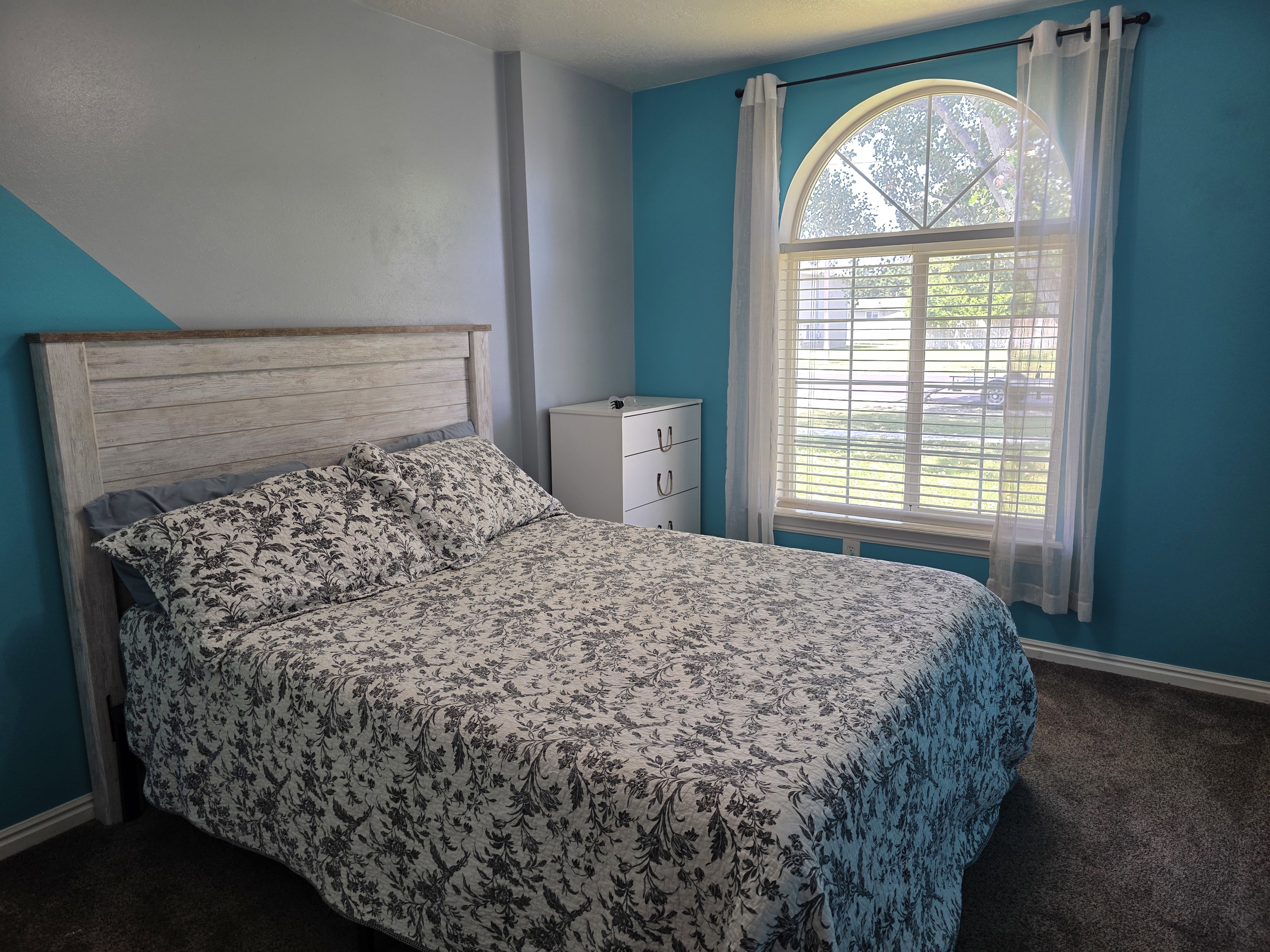 Room featuring an arched window with horizontal blinds, carpet flooring, and a white baseboard trim